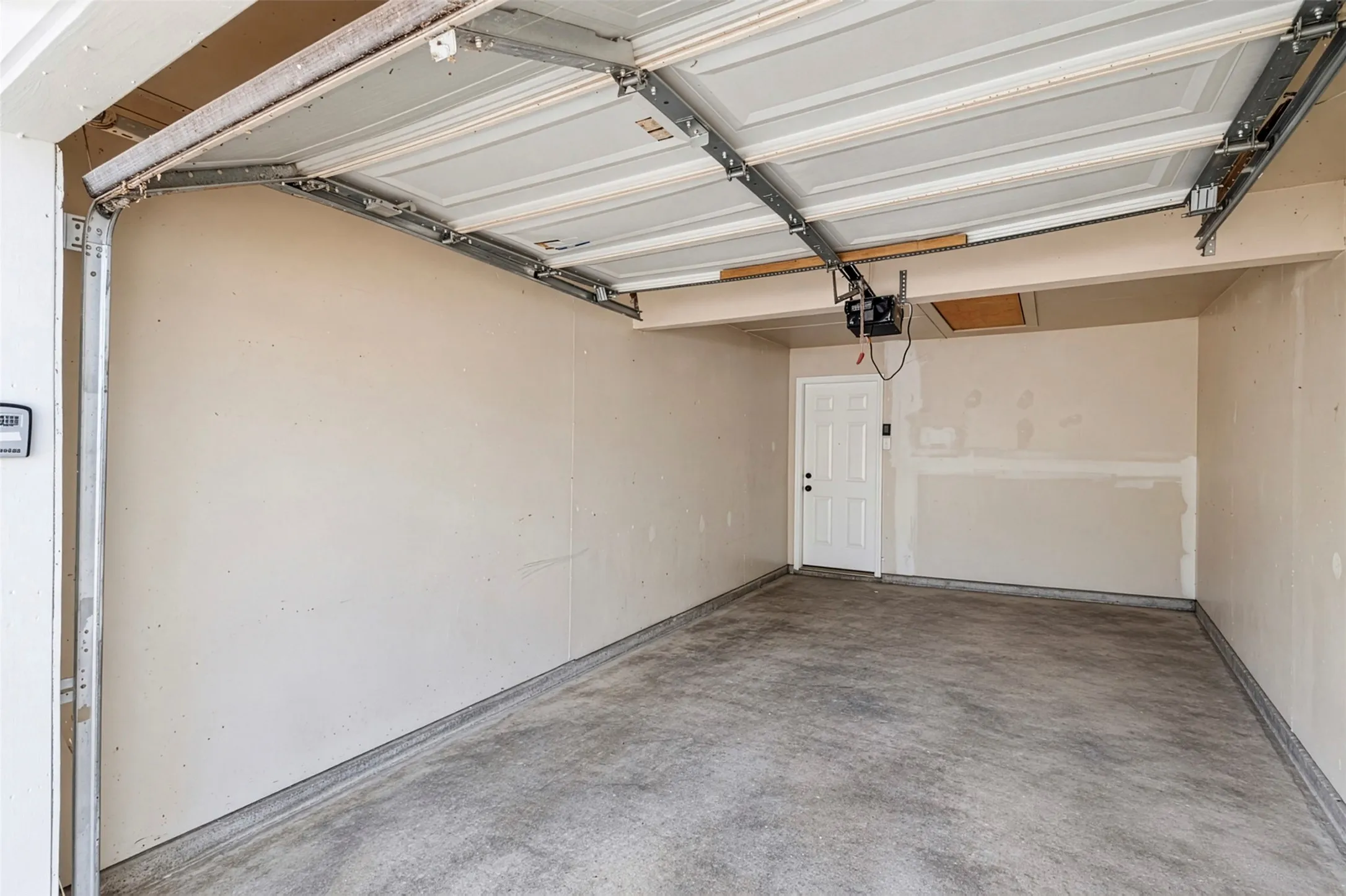 Attached garage with concrete flooring, automatic garage door opener, and interior access door