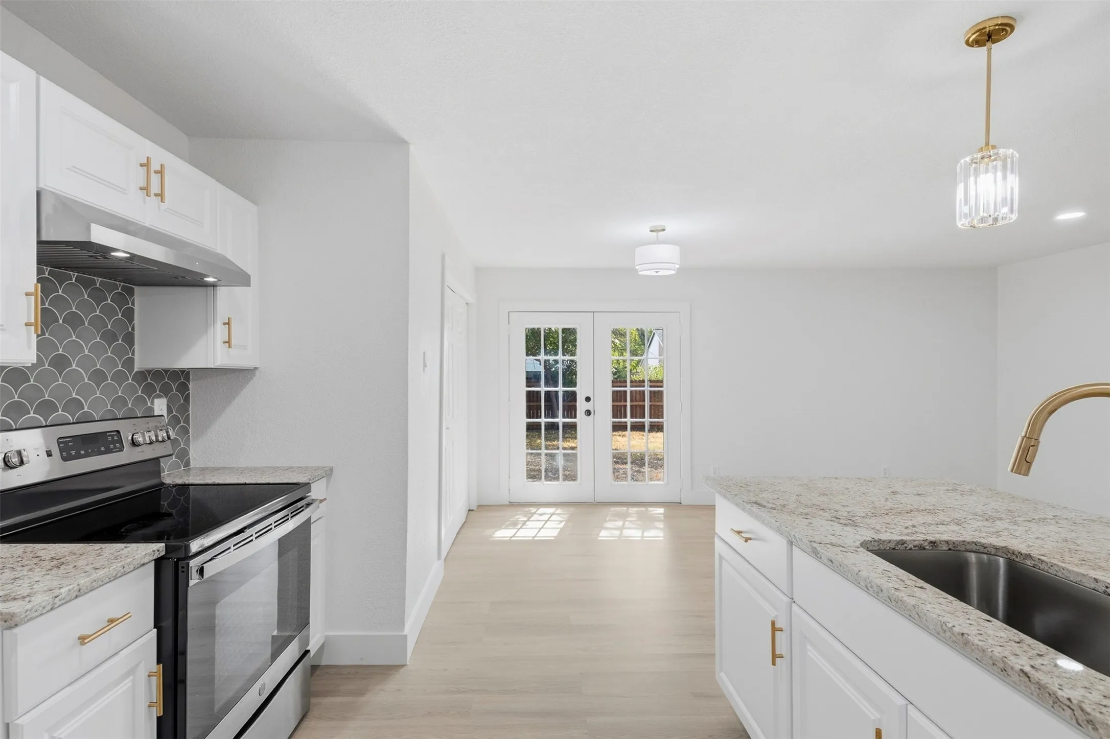 Kitchen featuring white cabinetry, light-colored countertops, stainless steel appliances, and a tiled backsplash
