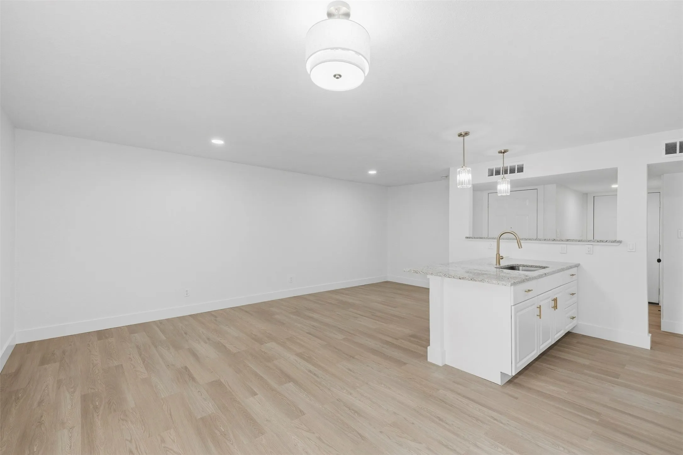 Kitchen island with white cabinetry, gold-finish hardware, and a granite countertop