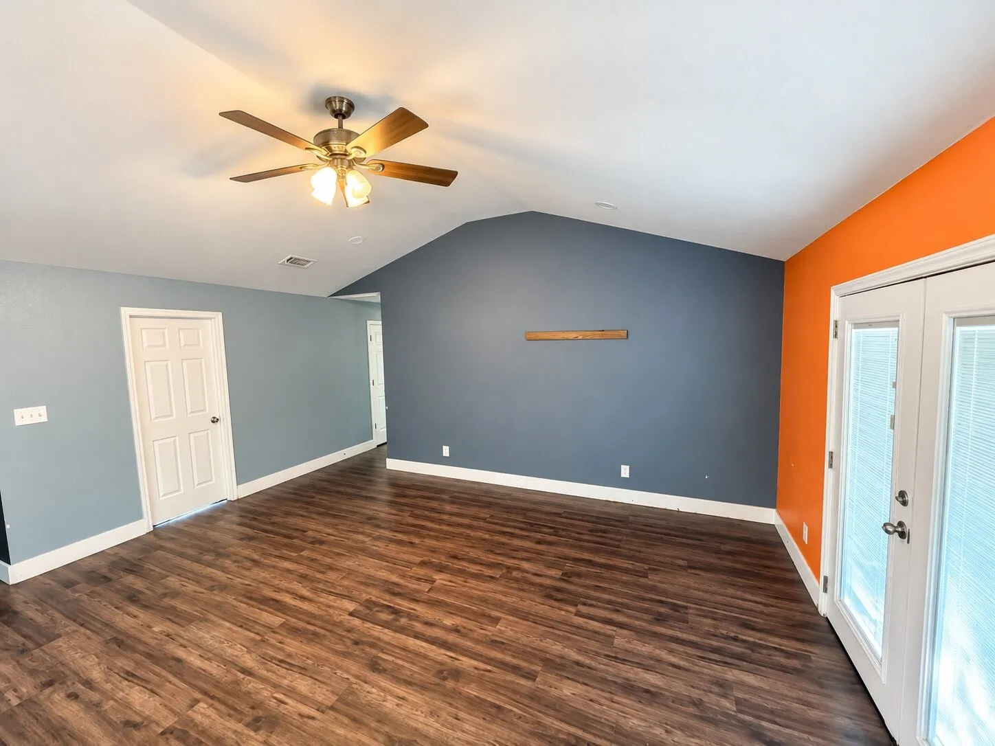 Vaulted ceiling with a ceiling fan, wood-finish flooring, two-panel interior door, and French doors