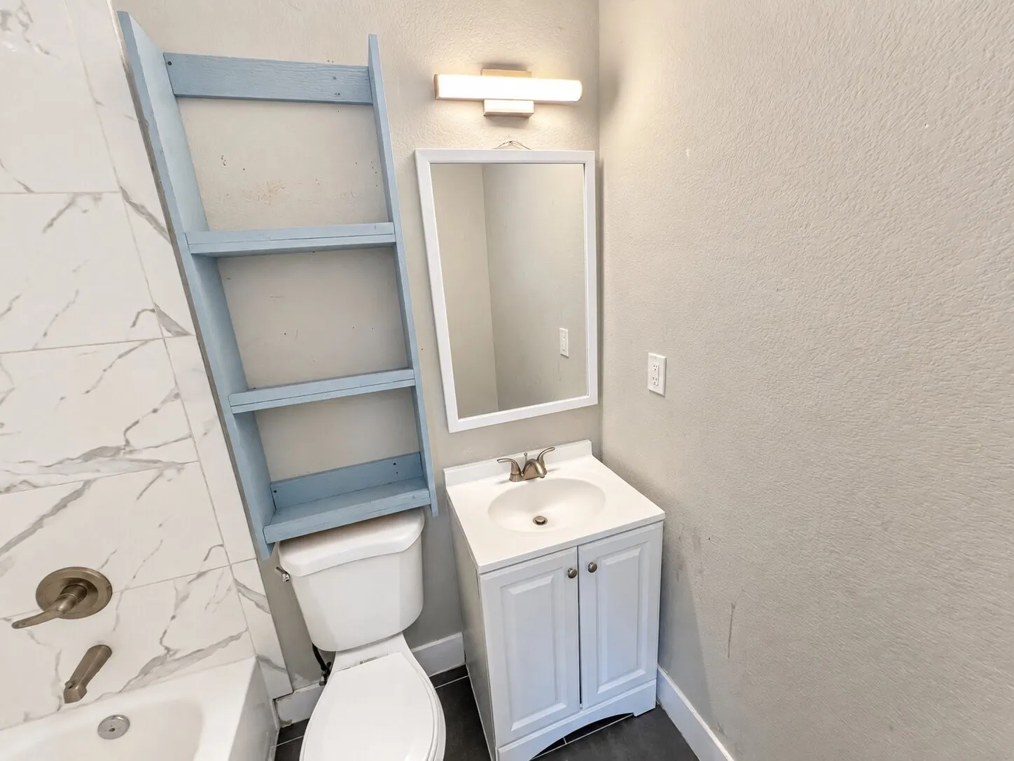 White vanity with an integrated sink, framed mirror, and a modern wall-mounted light fixture