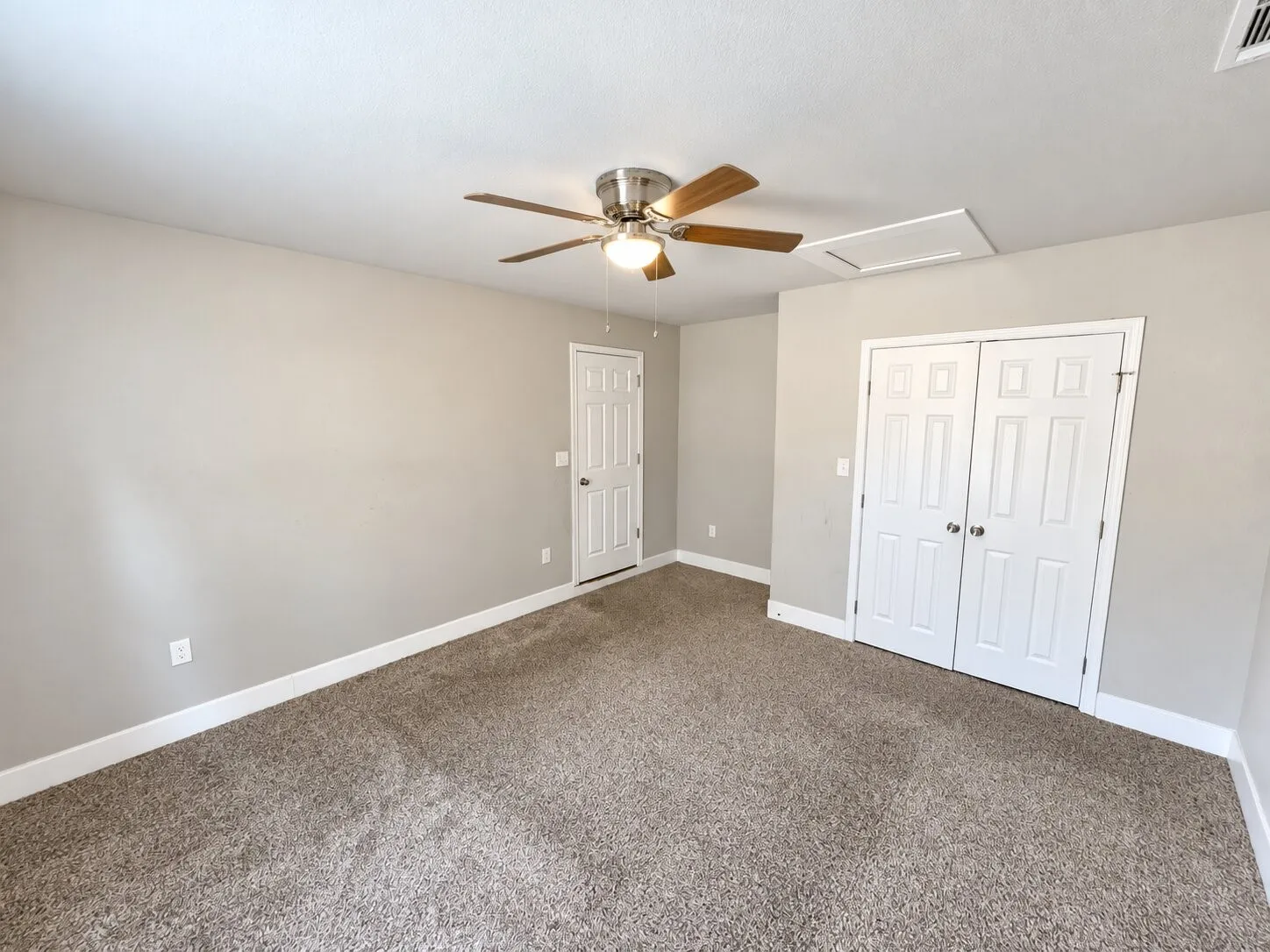 Neutral-toned wall paint, textured carpeting, modern ceiling fan with lighting, white paneled doors, and white trim