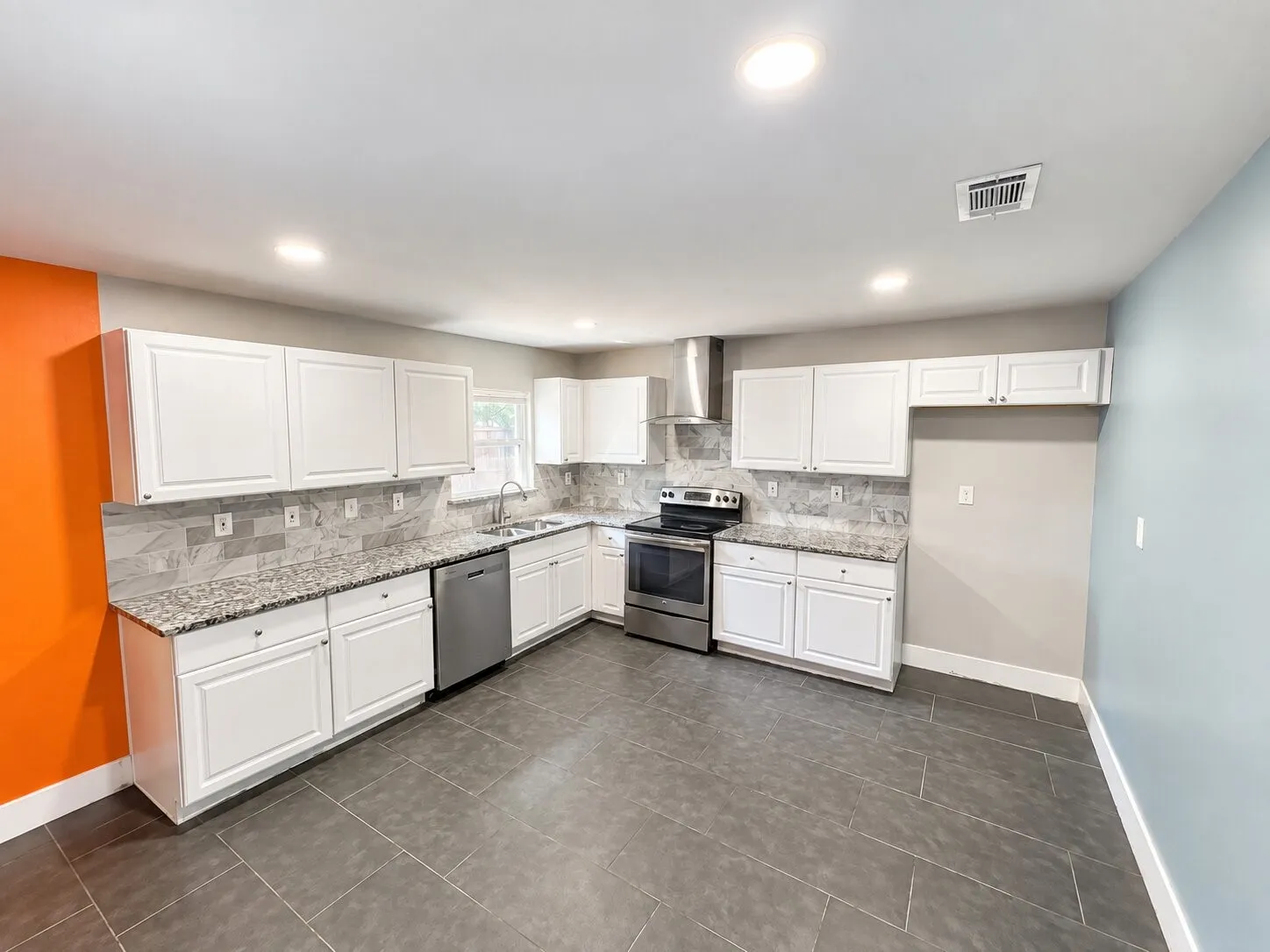Kitchen featuring white cabinetry, granite-style countertops, stainless steel appliances, tile flooring, and a tile backsplash