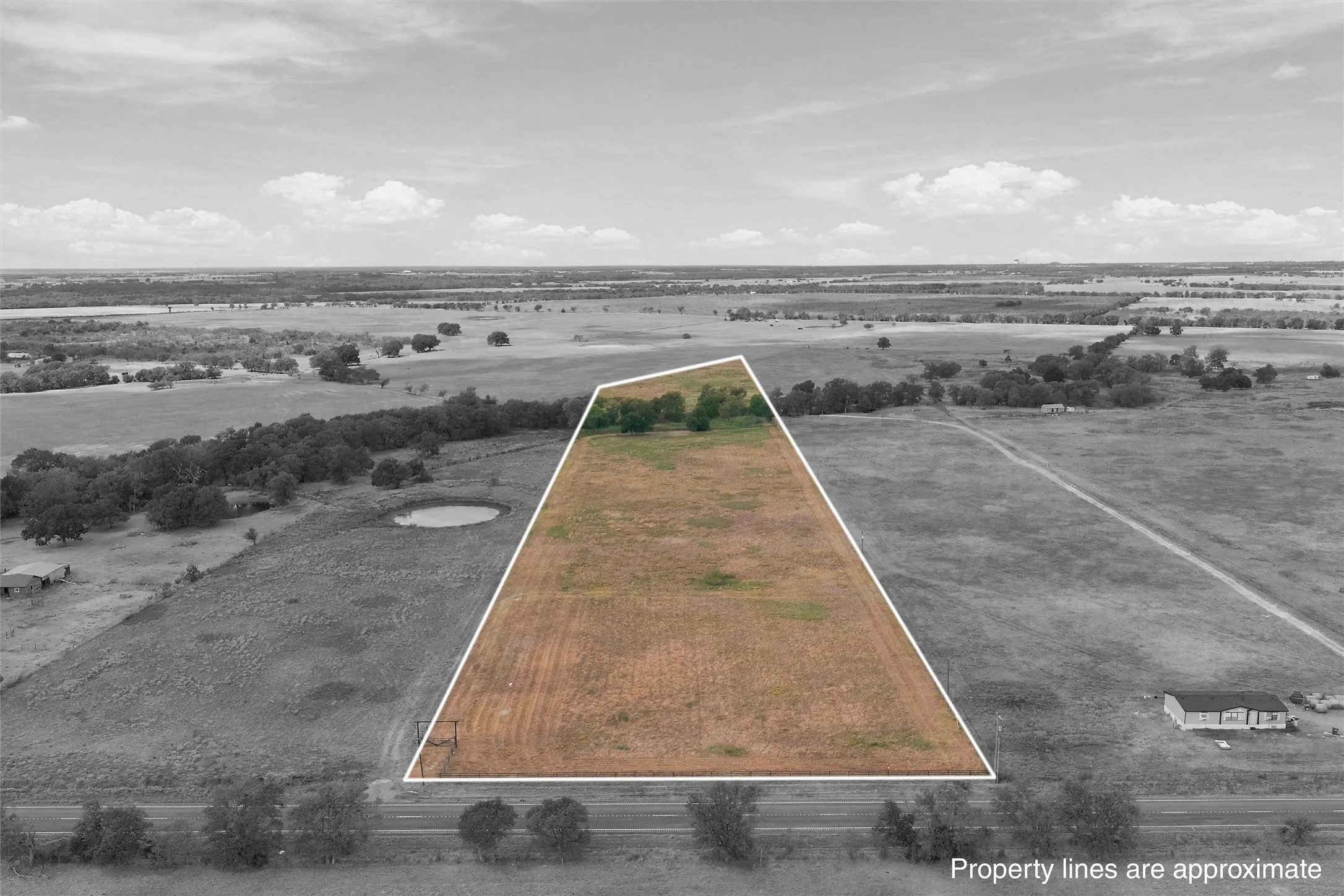Expansive land parcel with clear boundaries, some natural foliage, and direct road access