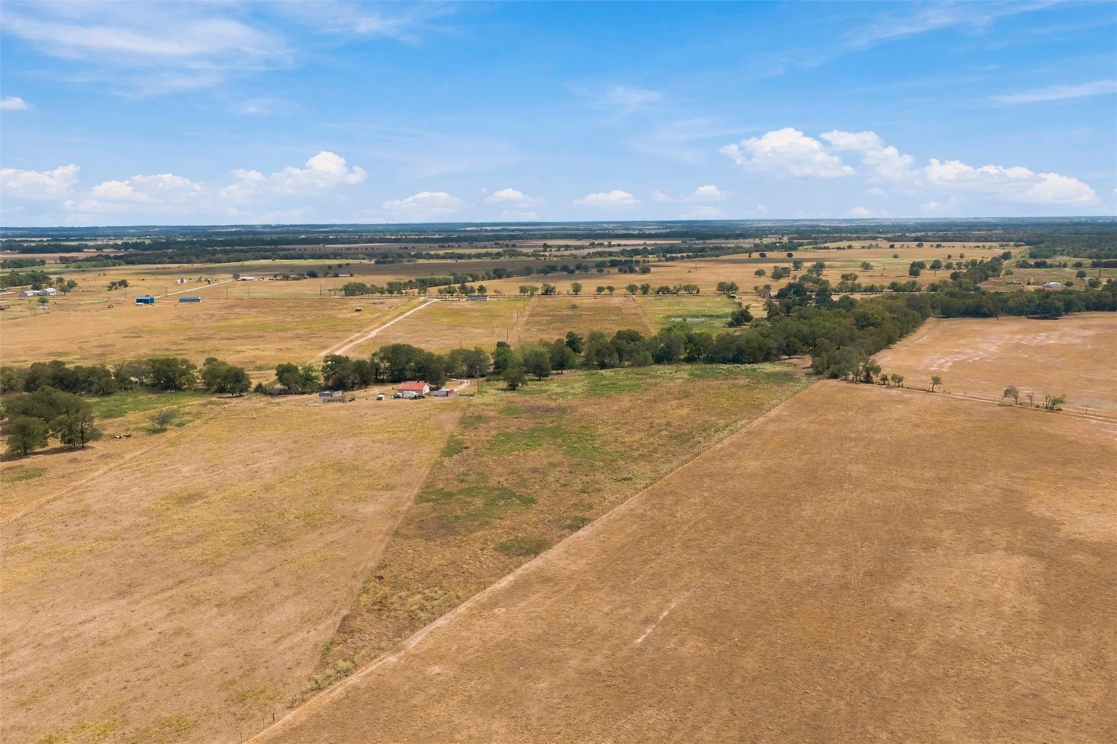 Expansive acreage featuring open fields, mature trees, and visible structures