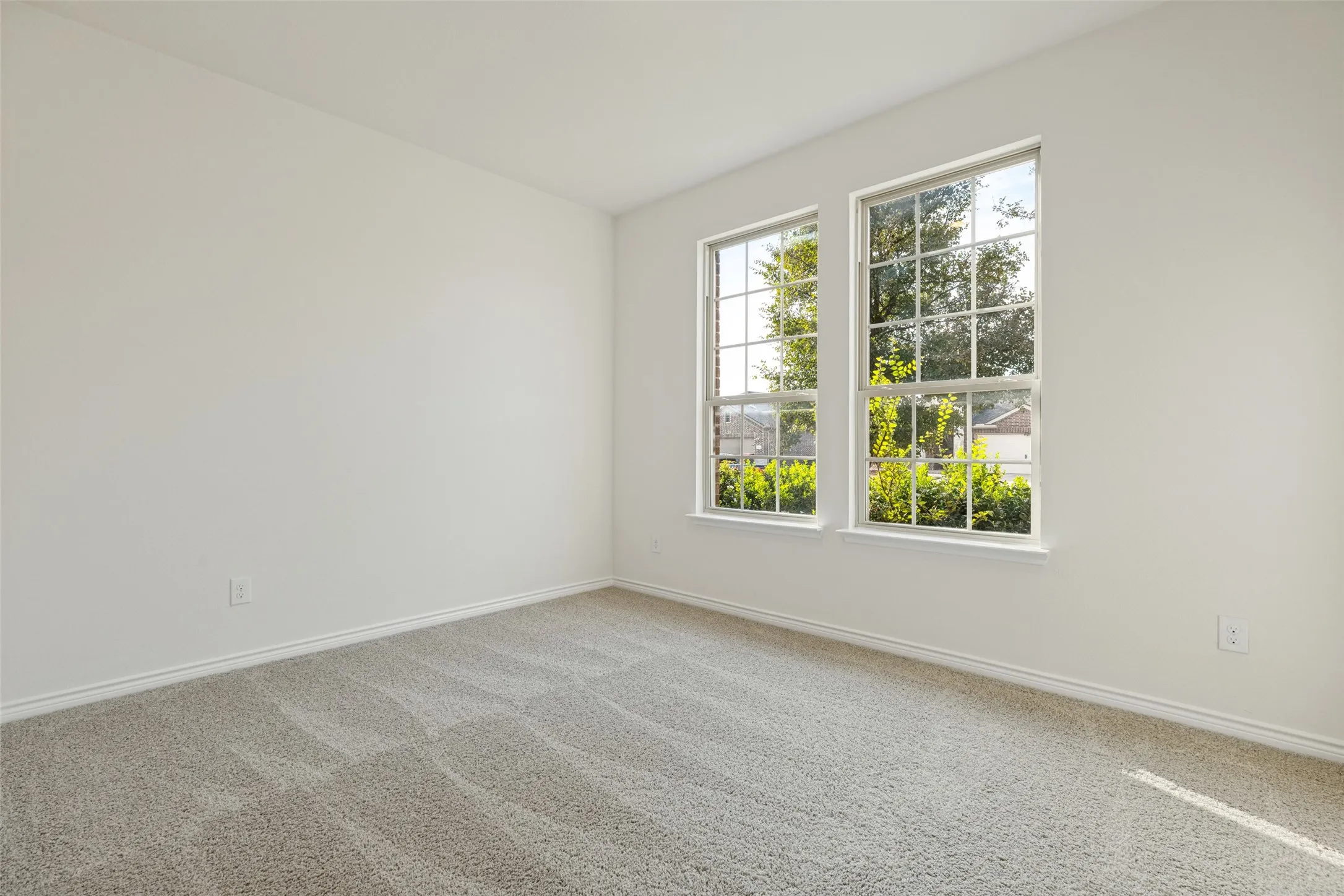 Neutral wall paint, plush carpet flooring, and two large multi-pane windows