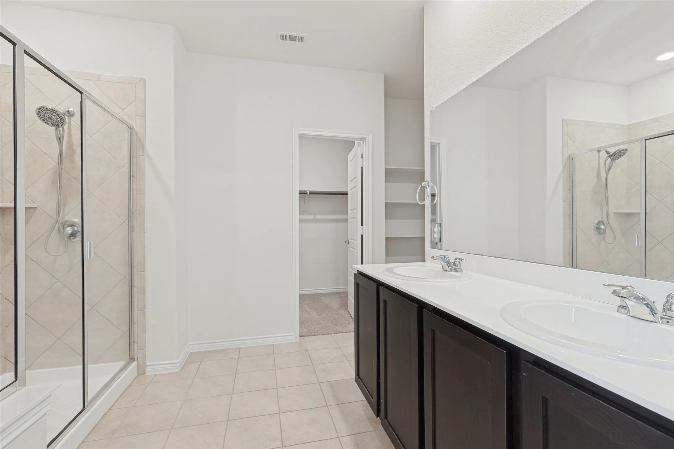 Dual vanity with white countertop, chrome fixtures, and dark wood-finish cabinetry