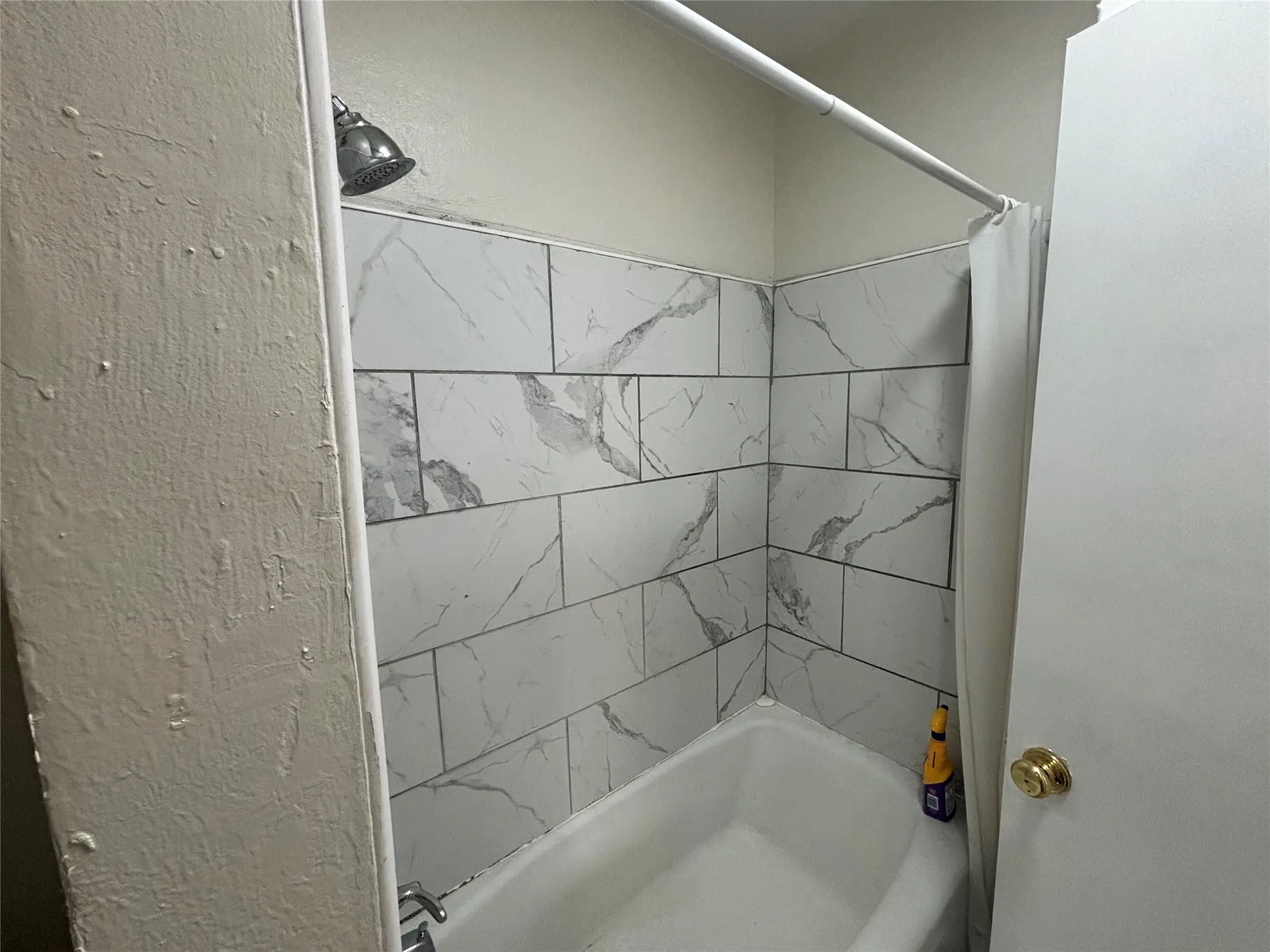Bathtub with subway-style wall tiles and a chrome shower head