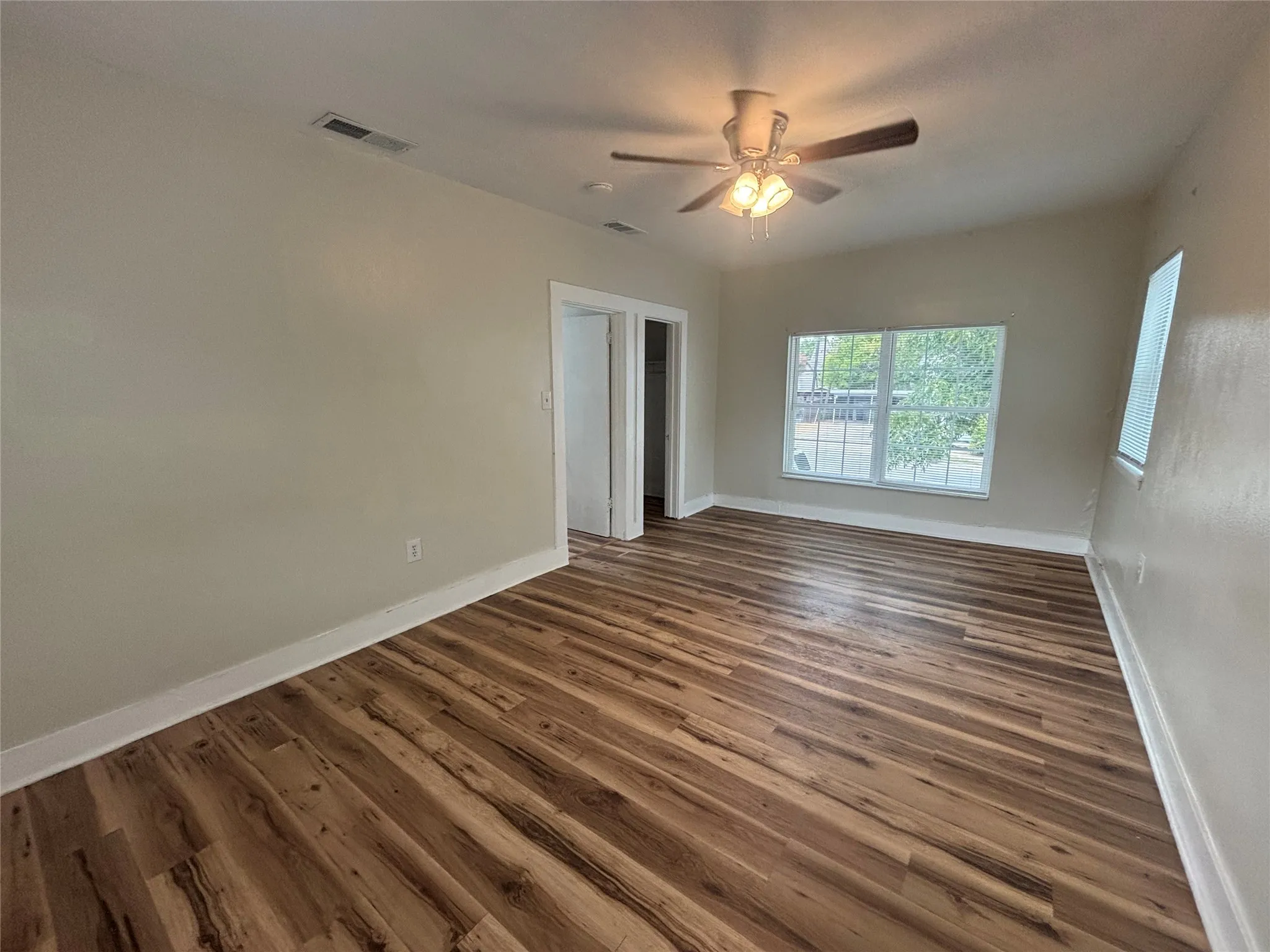 Wood-finish flooring, white trim, recessed lighting, ceiling fan with light fixture, and windows