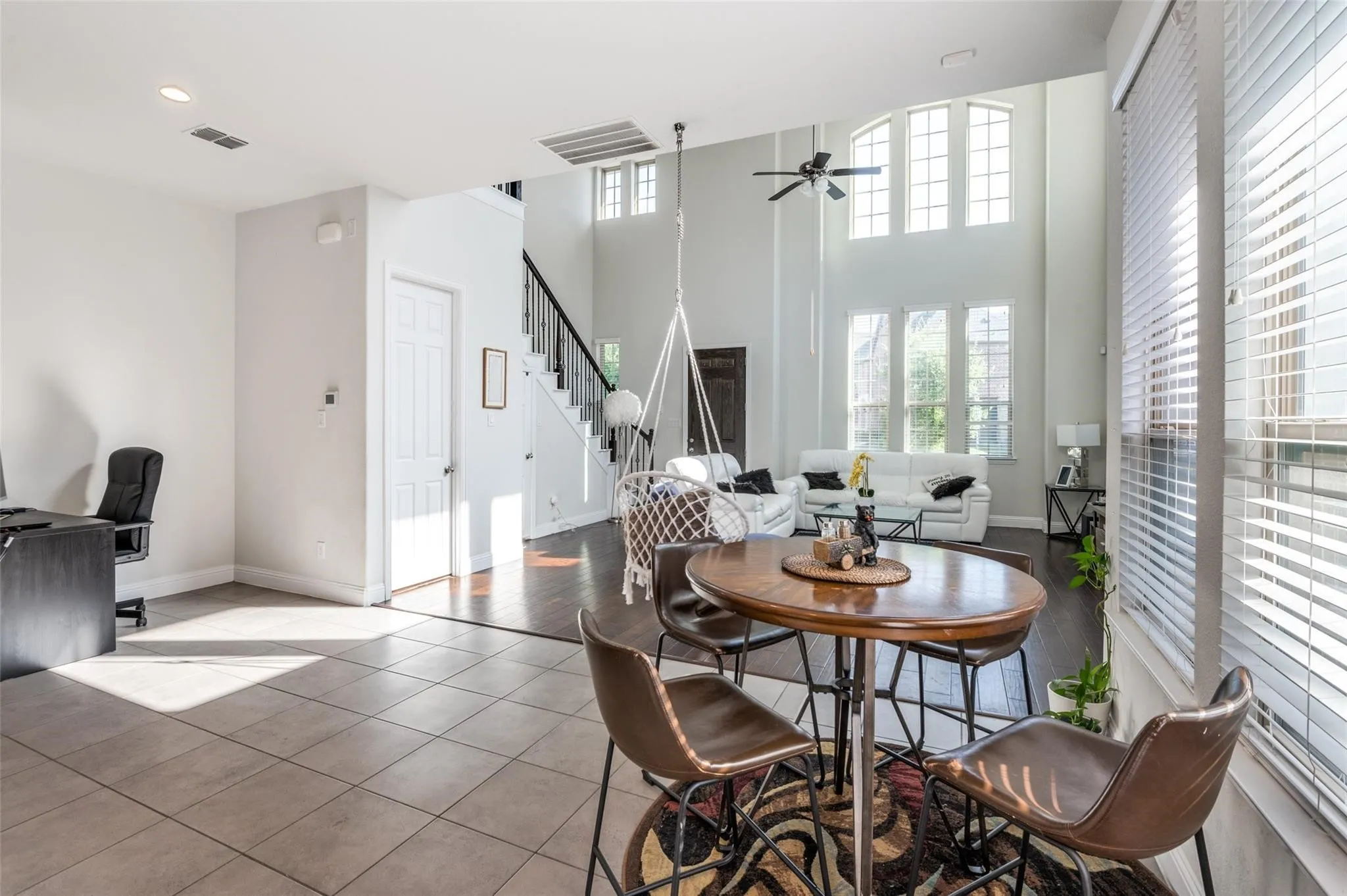 Two-story living area with high ceilings, large arched windows, dark wood-finish flooring, and a staircase with dark wood-finish handrails