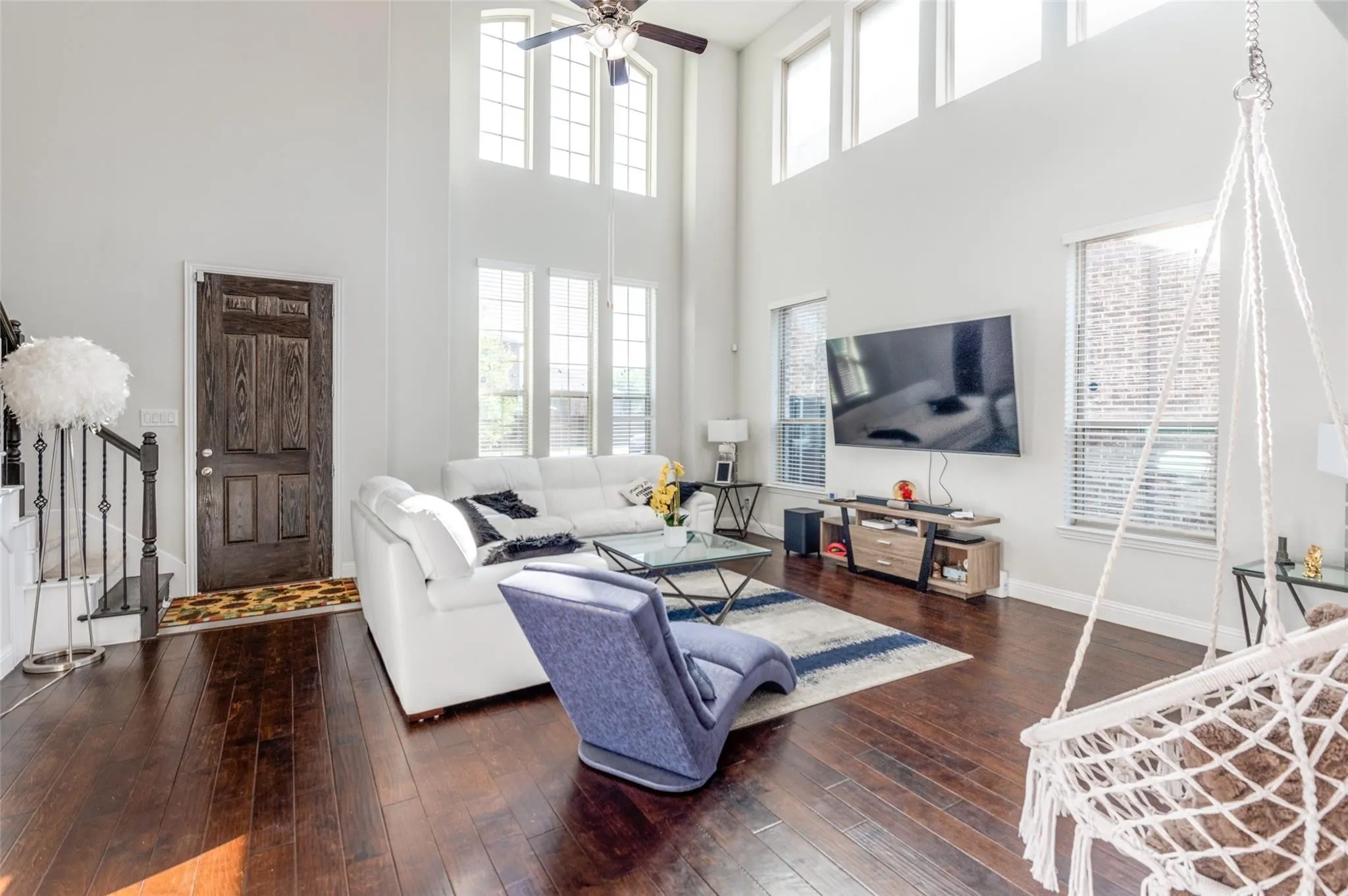 High ceilings, rich wood-finish flooring, abundant natural light from large windows, and a wood-paneled entry door