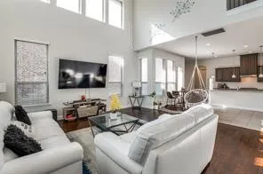 Open-concept living space featuring high ceilings, wood-finish flooring, and a kitchen with dark cabinetry