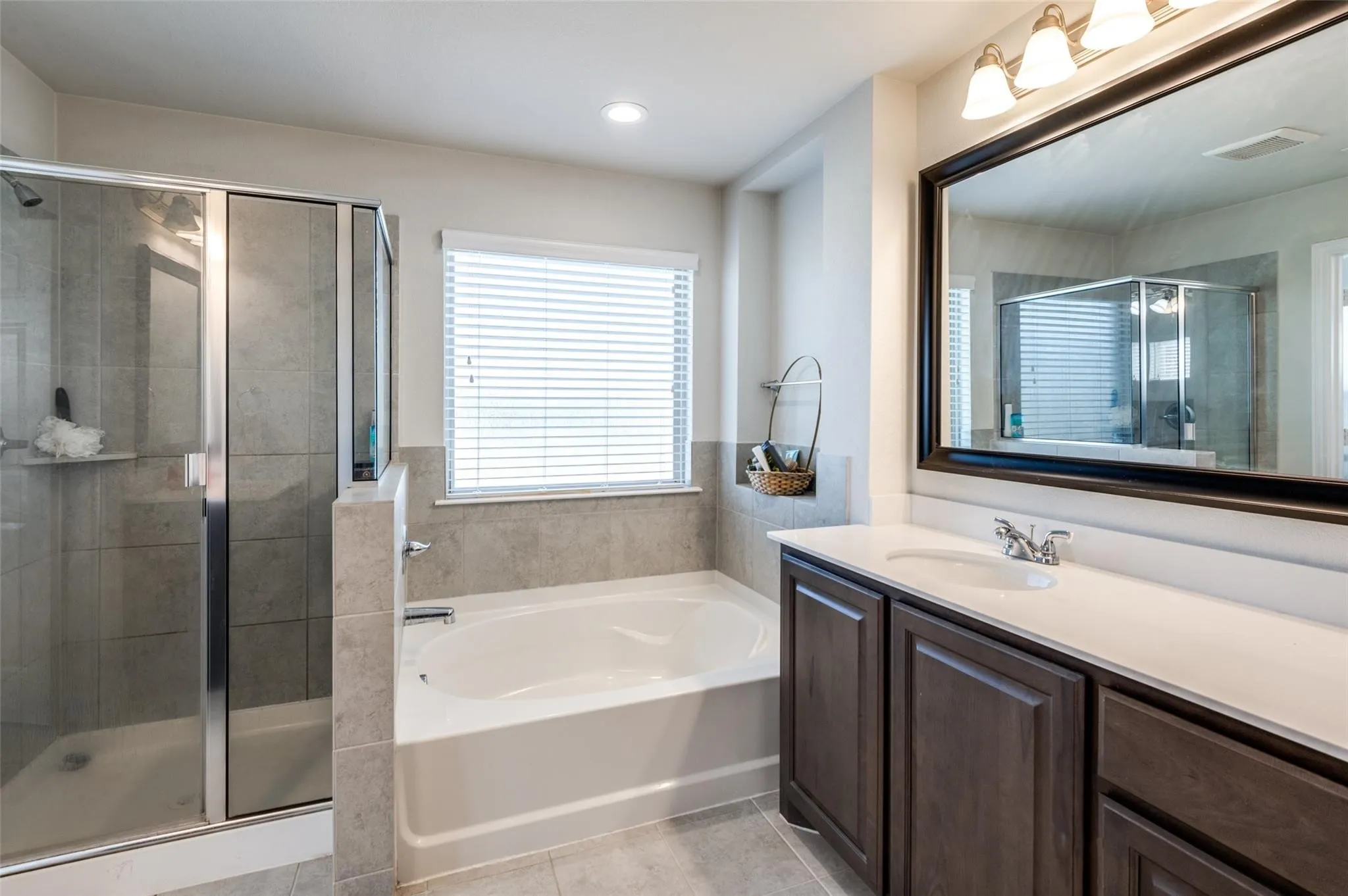Walk-in shower with glass enclosure, separate soaking tub, single vanity with integrated sink, and dark wood-finish cabinetry