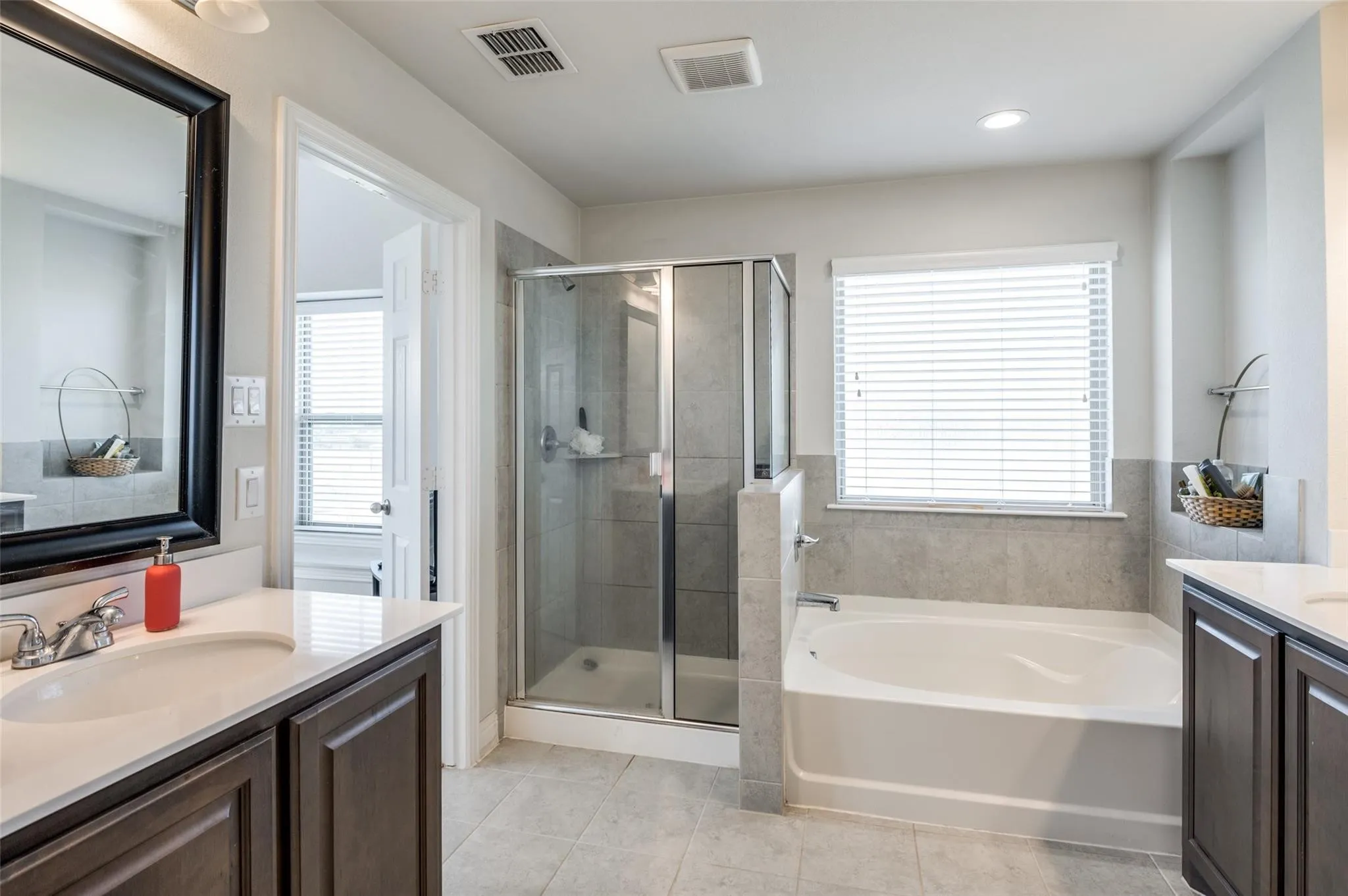 Dual vanity with undermount sinks, a built-in soaking tub, and a separate glass-enclosed shower