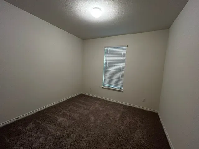Spare room featuring dark carpet