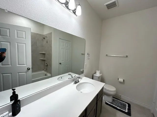 Full bathroom with tiled shower / bath, vanity, and toilet
