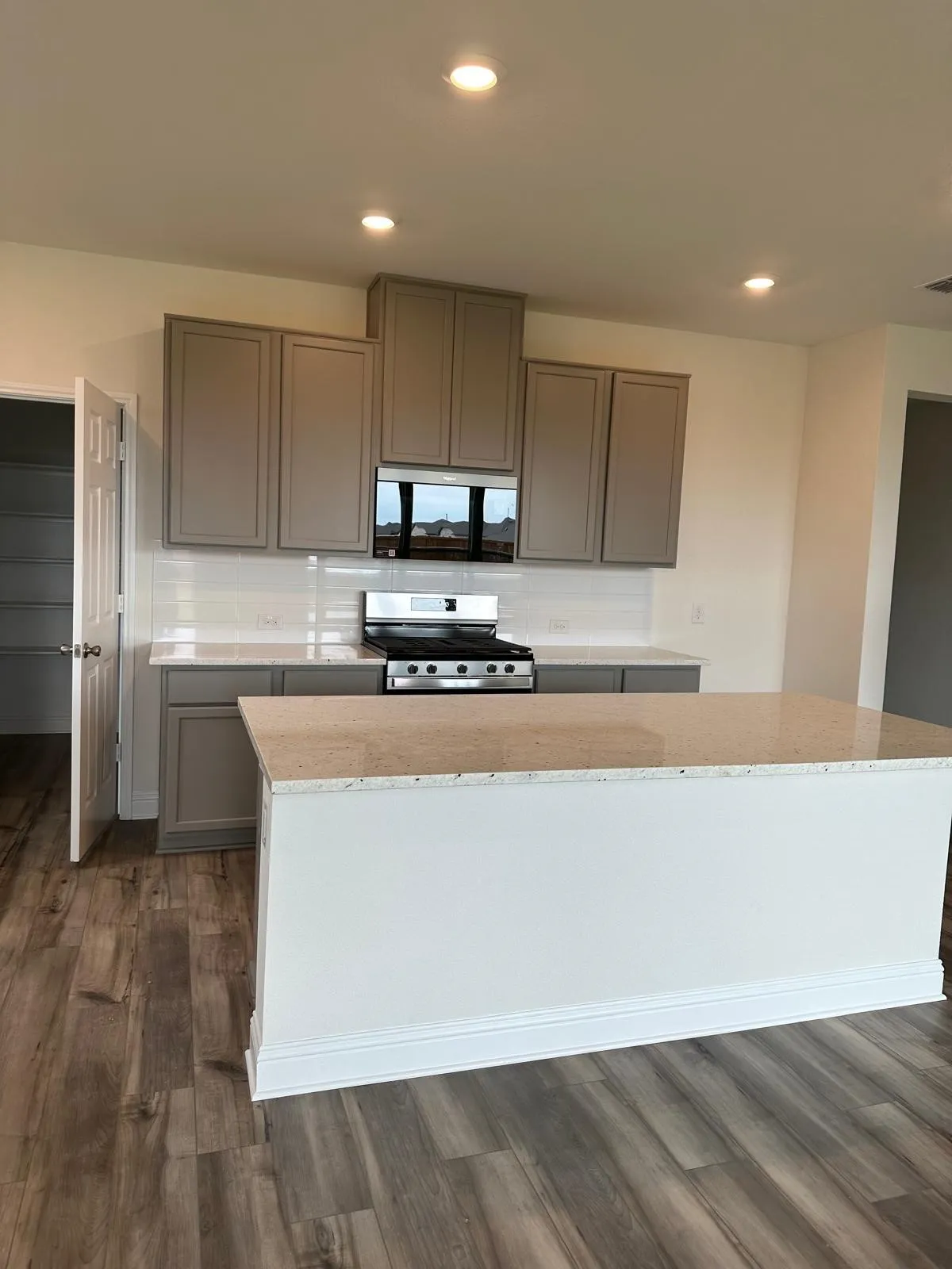 Kitchen with a kitchen island, decorative backsplash, light stone countertops, dark wood-type flooring, and stainless steel range oven