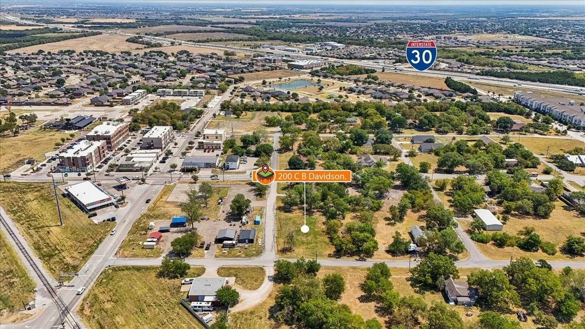 Aerial perspective showing surrounding roads, nearby commercial buildings, residential areas, and Interstate 30