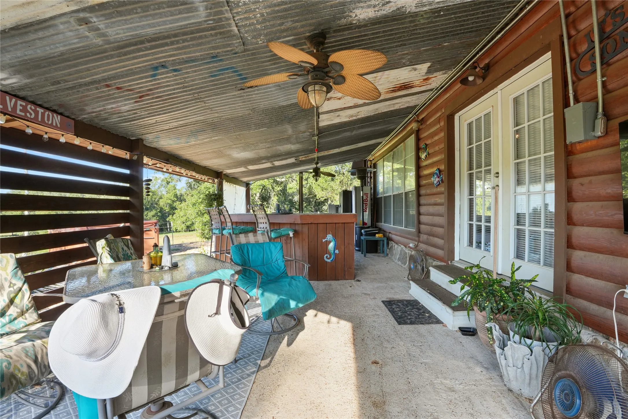 Covered patio featuring a corrugated metal ceiling, wood-paneled walls, French doors, and a built-in bar
