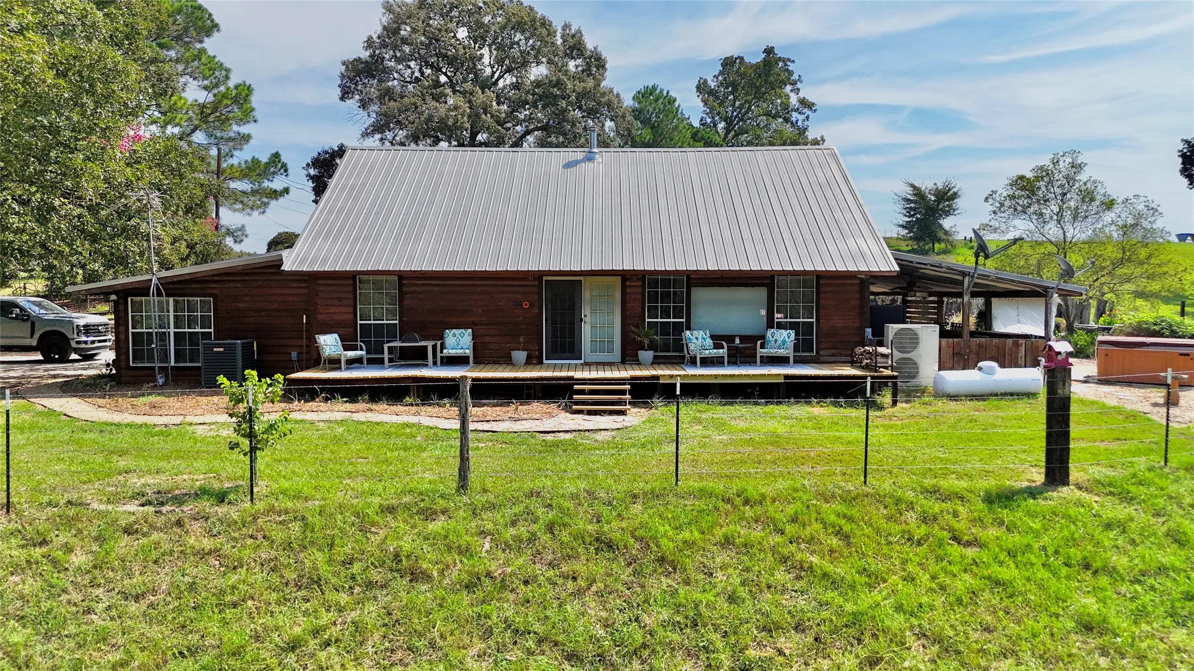 Wood-sided structure featuring a metal roof, an elevated wooden deck, and a hot tub