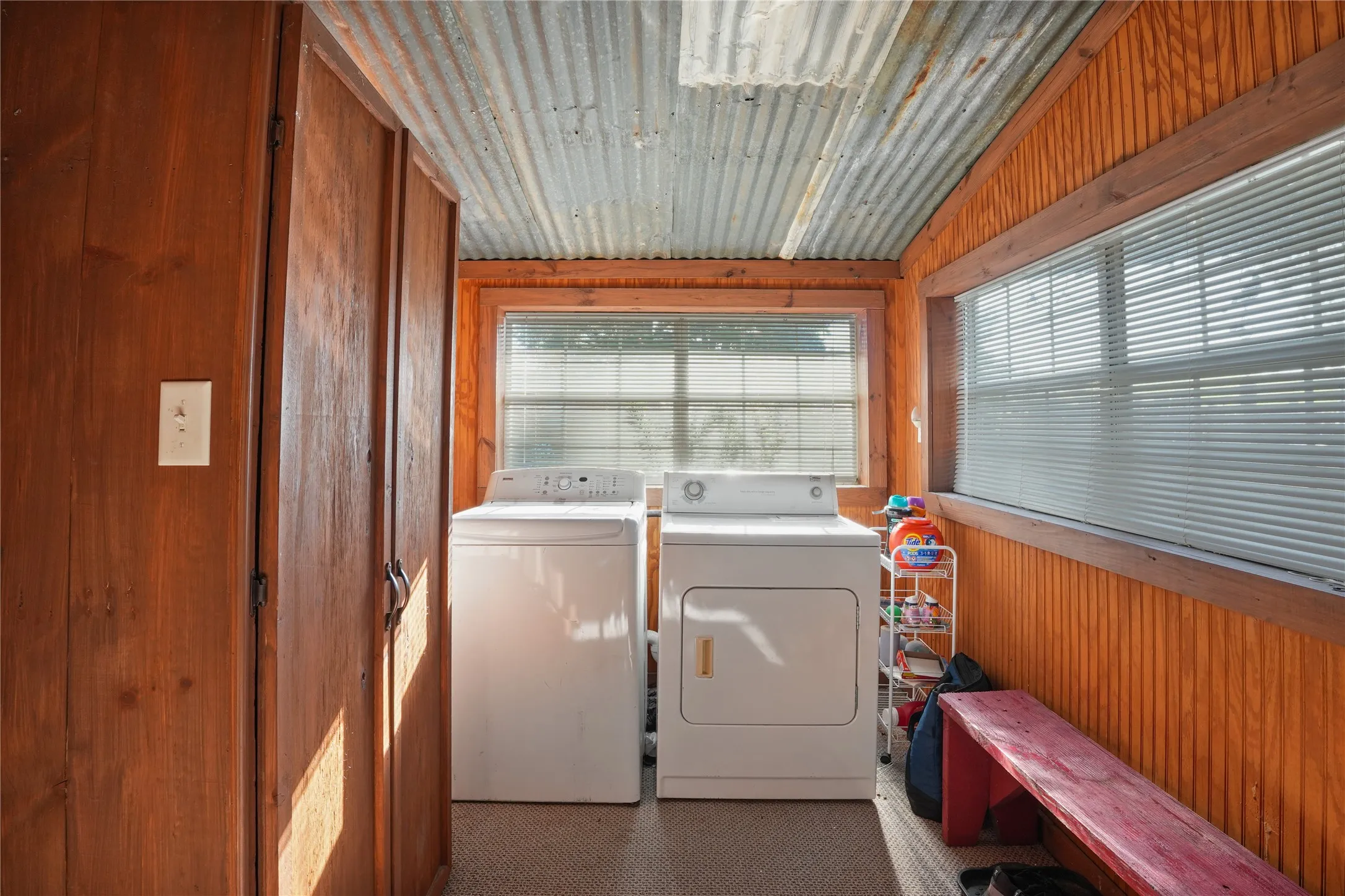 Laundry area featuring wood-paneled walls, a corrugated metal ceiling, and built-in storage cabinets