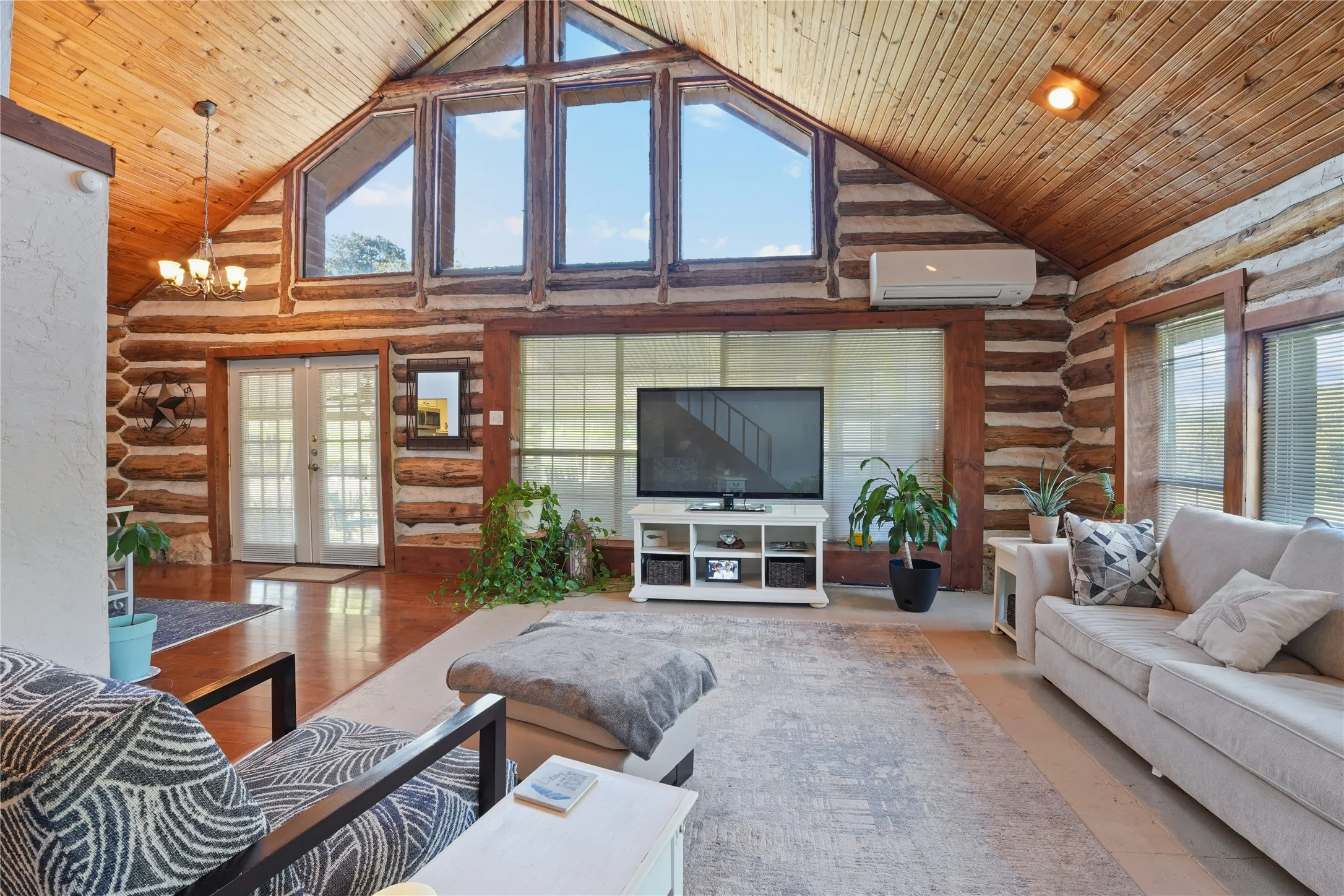 Vaulted wood-paneled ceiling, exposed log walls, and multiple windows with upper transoms