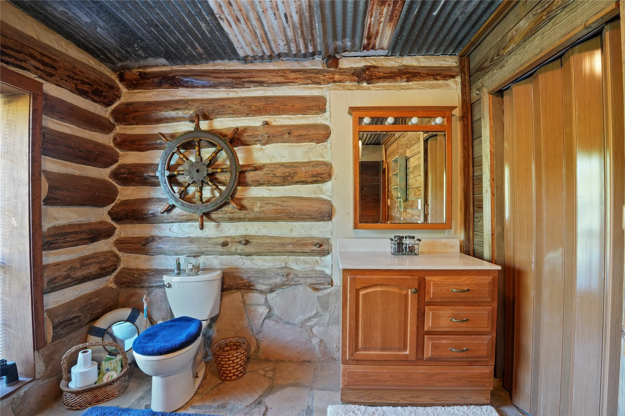 Rustic interior featuring log wall construction and a stone-clad base