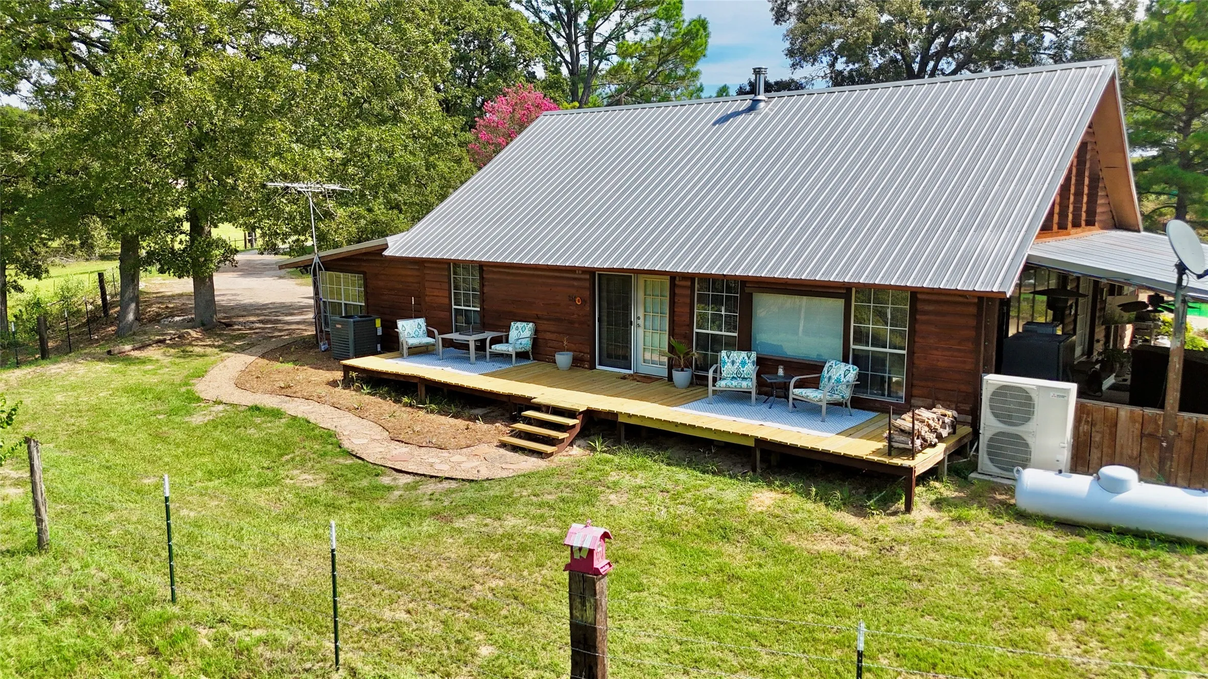 Wood-sided residence featuring a metal roof, an expansive deck, and a gravel pathway