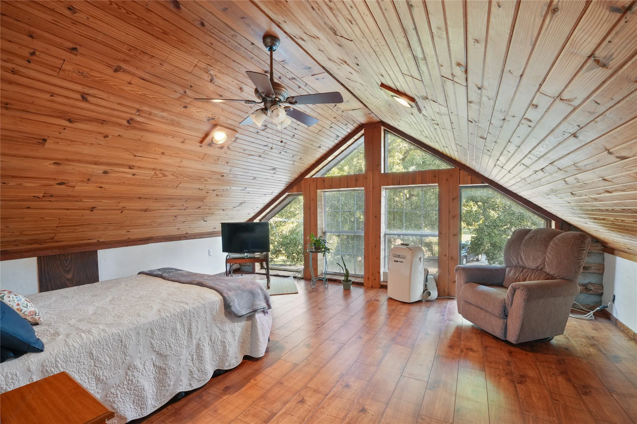 Vaulted wood-paneled ceiling, wood-finish flooring, ceiling fan, and prominent A-frame windows