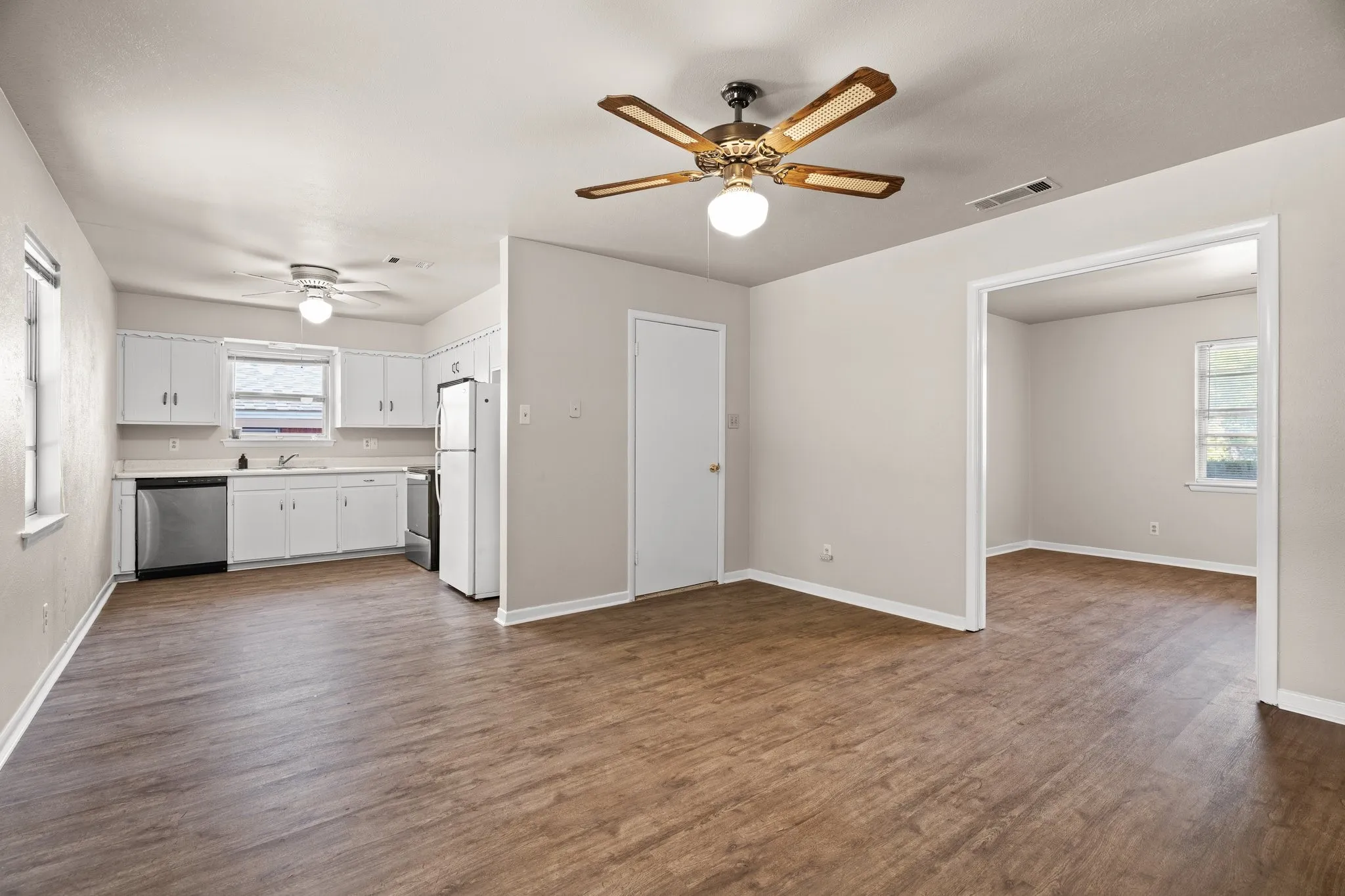 Unfurnished living room featuring ceiling fan, plenty of natural light, and dark wood-type flooring