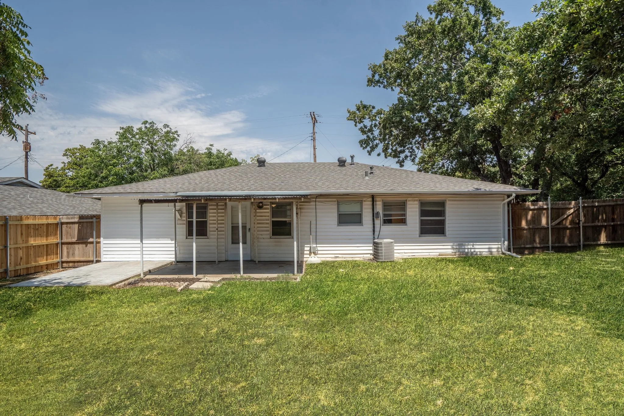 Rear view of house featuring a yard, central air condition unit, and a patio area