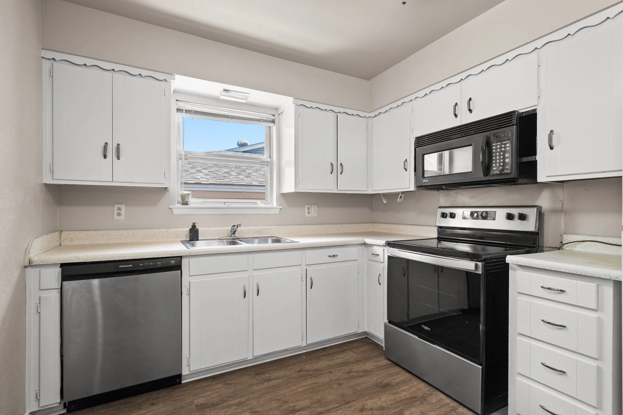 Kitchen with appliances with stainless steel finishes, sink, dark hardwood / wood-style flooring, and white cabinetry