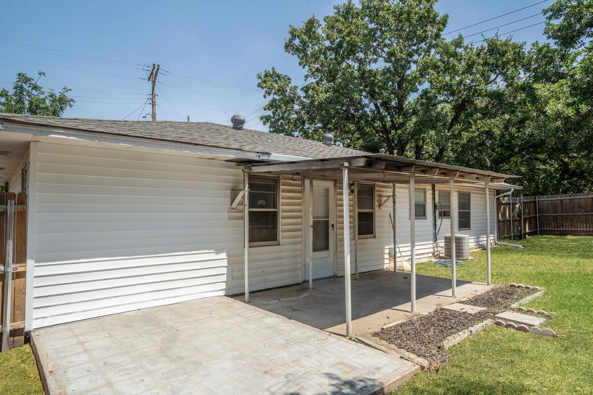 View of front of property with a front lawn, central AC unit, and a patio area