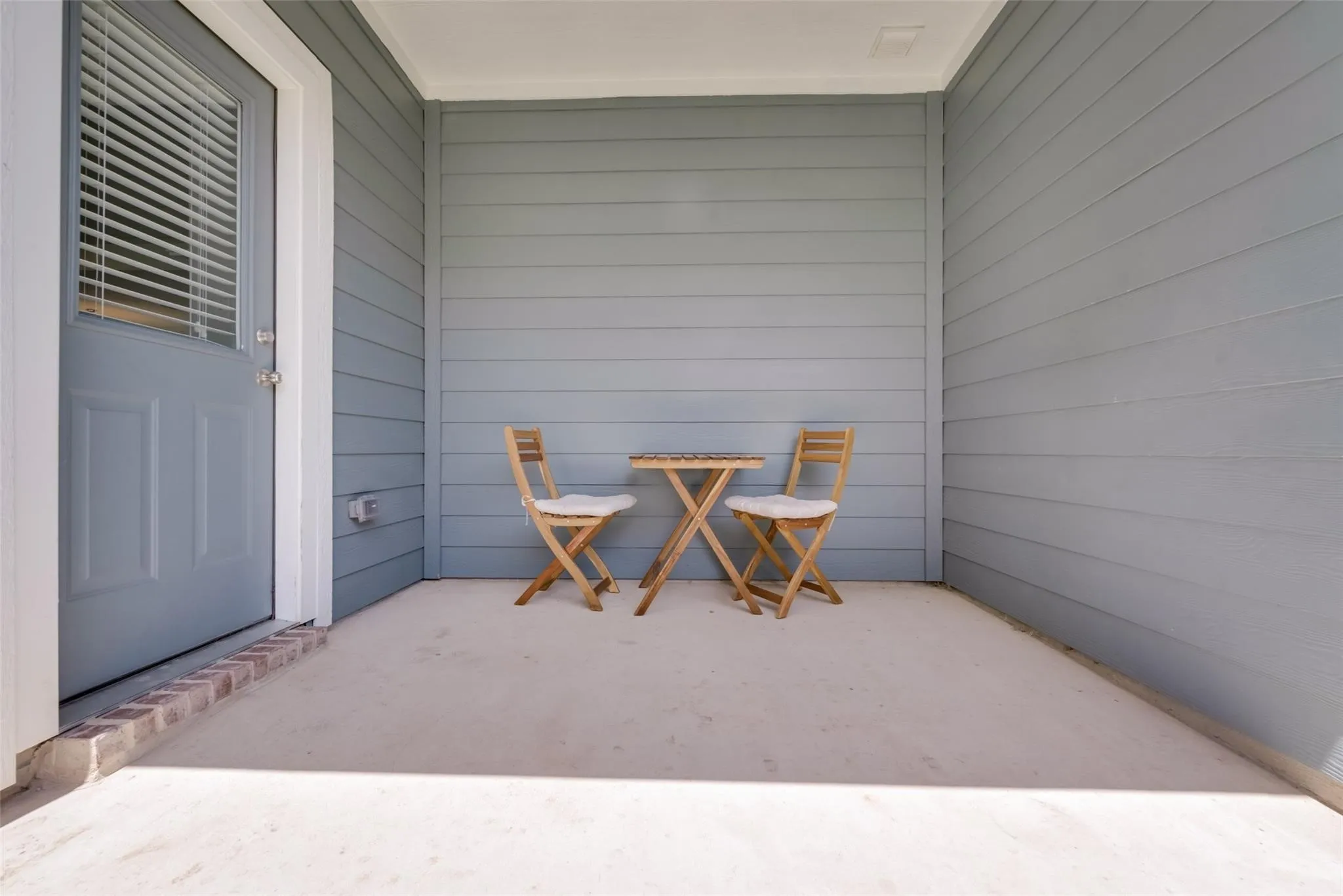 Covered outdoor patio with light gray siding and a concrete surface
