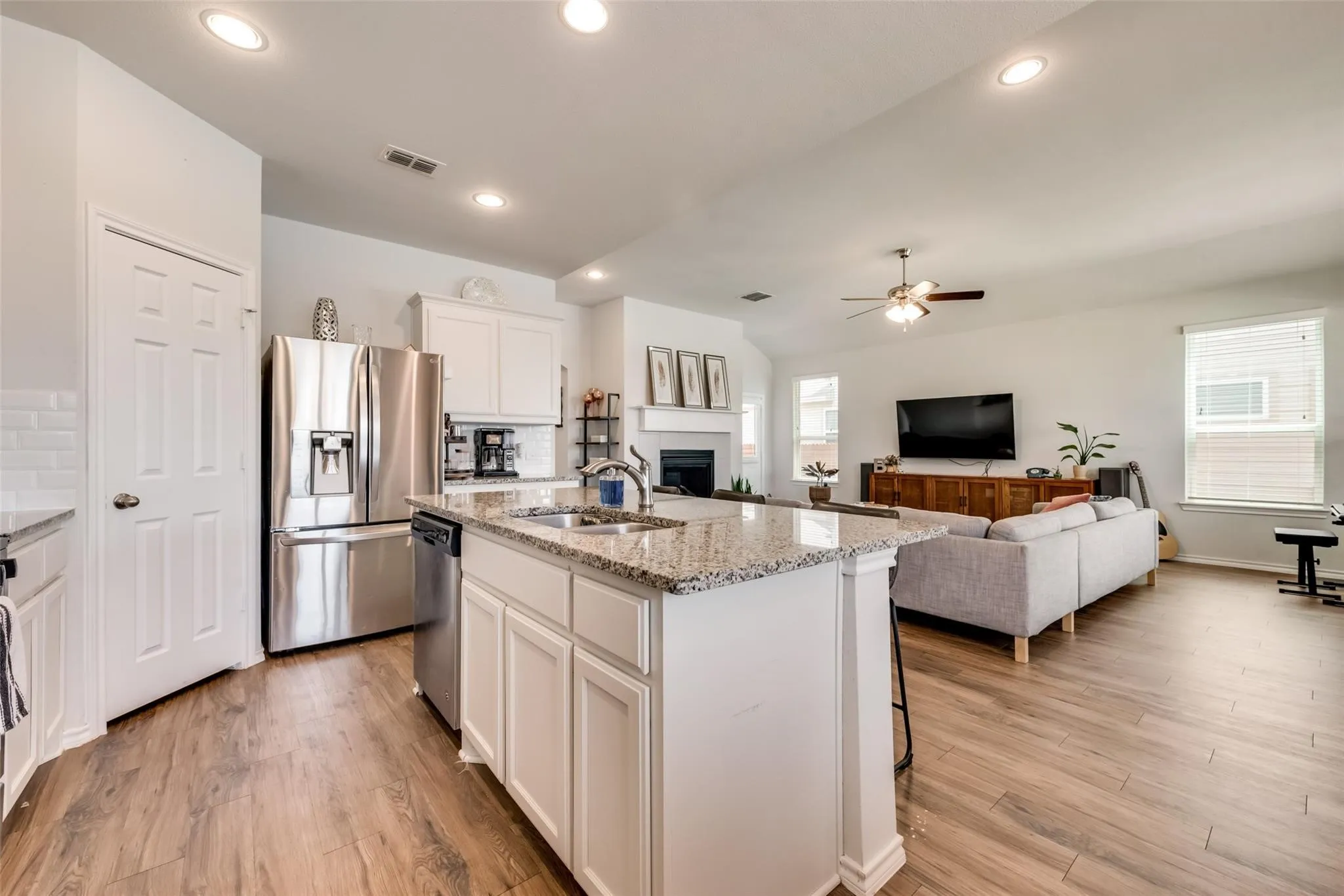 Open-concept kitchen featuring an island with a sink, white cabinetry, and stainless steel appliances