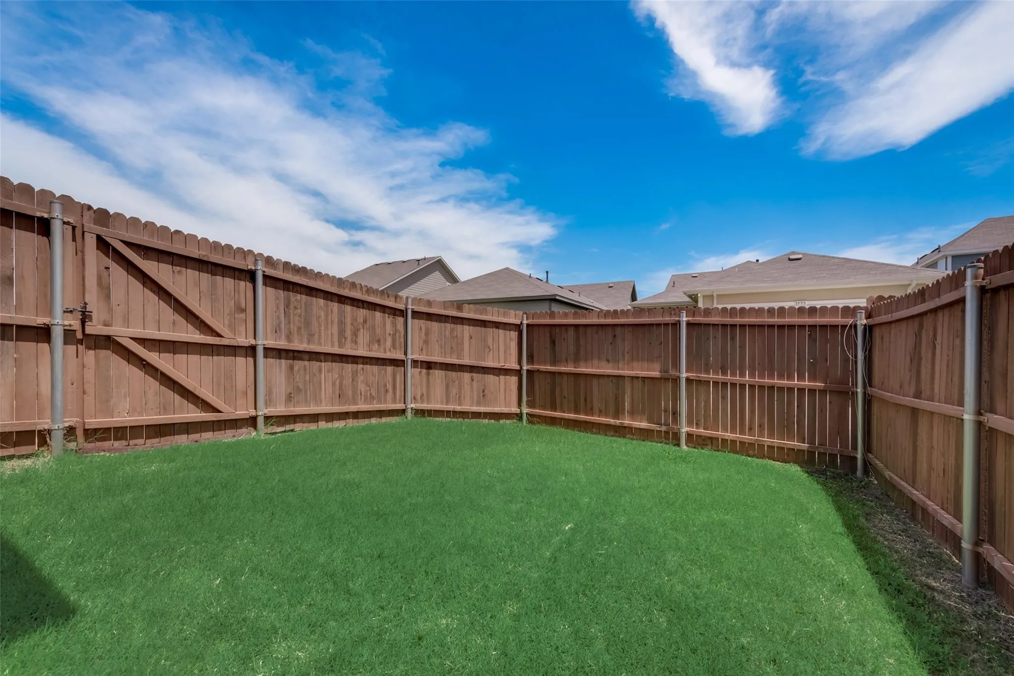 Fenced backyard featuring a wood privacy fence with metal posts and a grass lawn