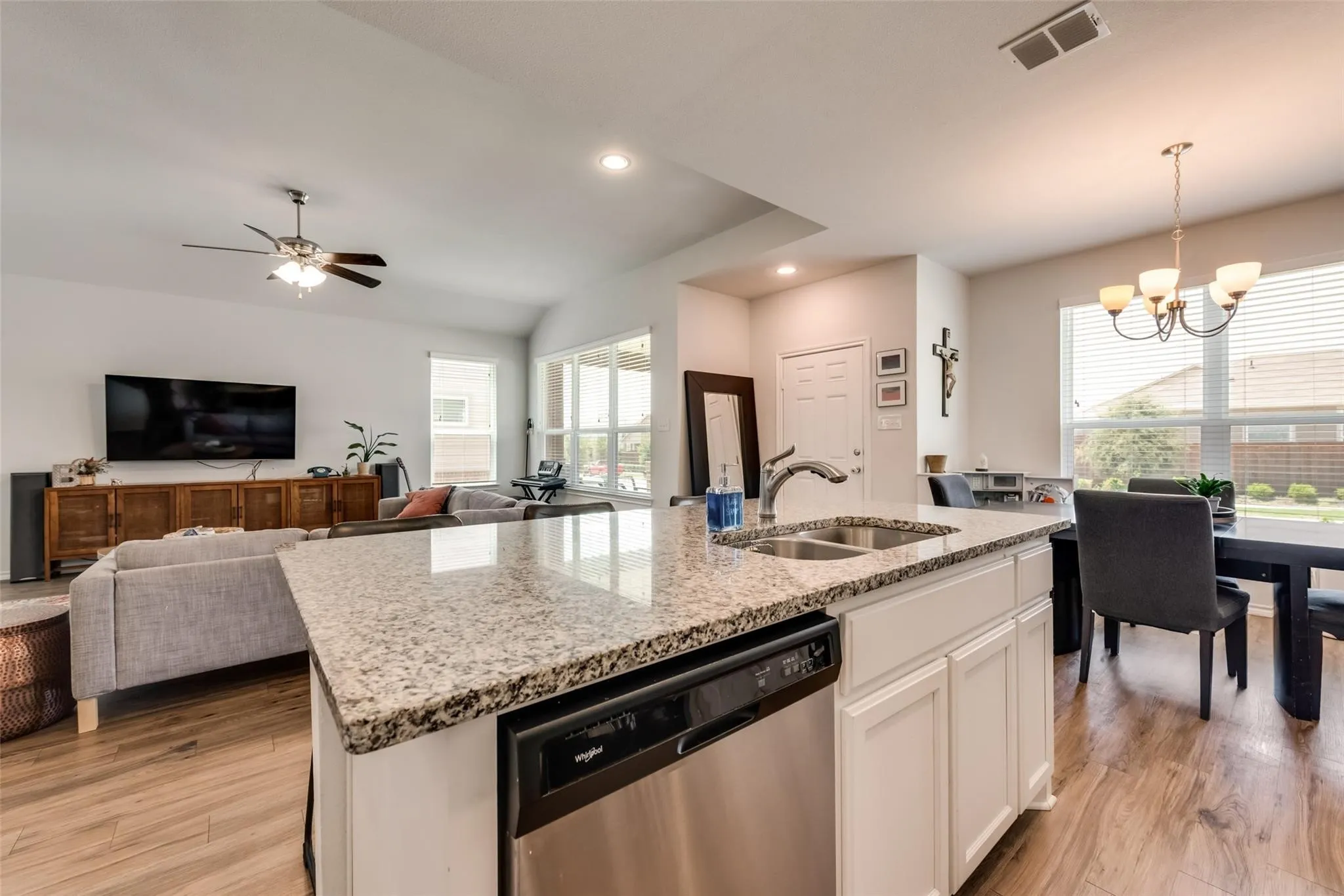 Kitchen island featuring a double-basin sink, stainless steel dishwasher, and a stone countertop