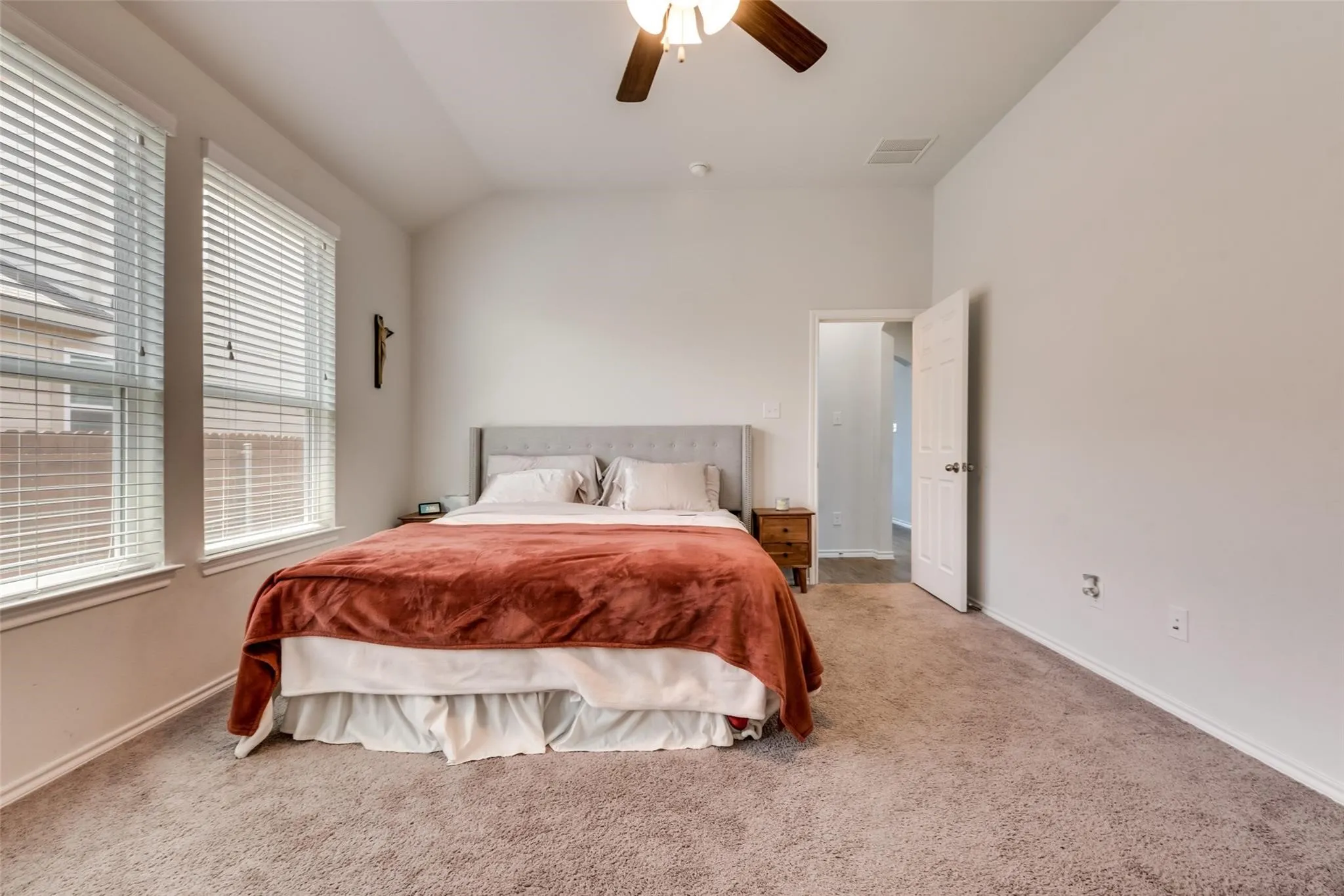 Recessed ceiling with an attached ceiling fan, two windows with blinds, and carpet flooring