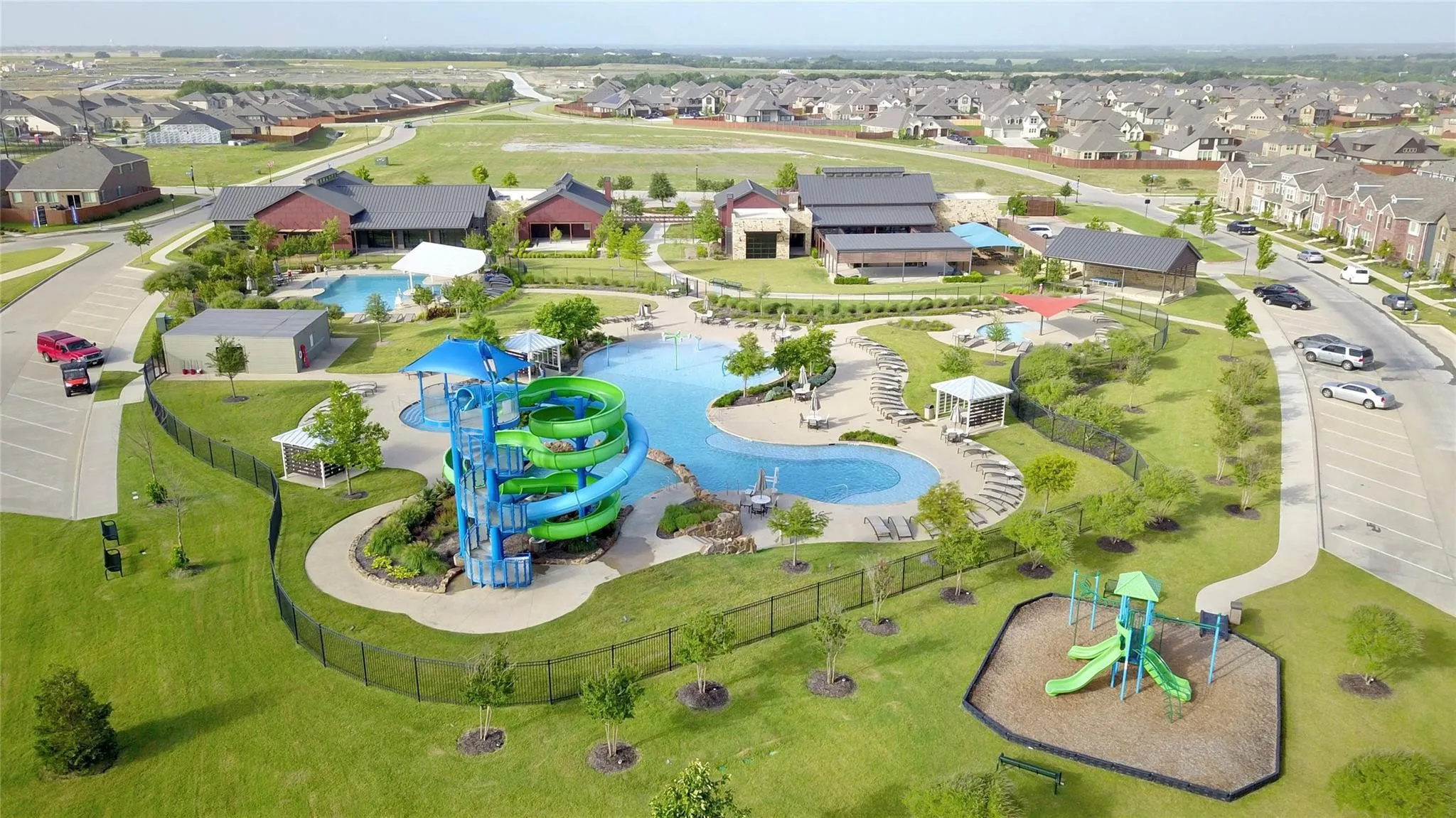 Community recreation area featuring multiple swimming pools, water slides, a playground, and extensive green spaces