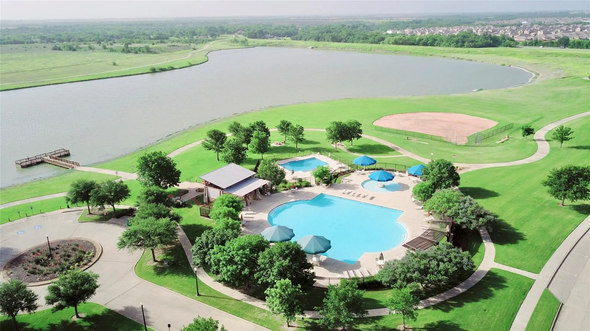 Community amenities featuring multiple swimming pools, waterfront access with a dock, a baseball field, and extensive walking paths