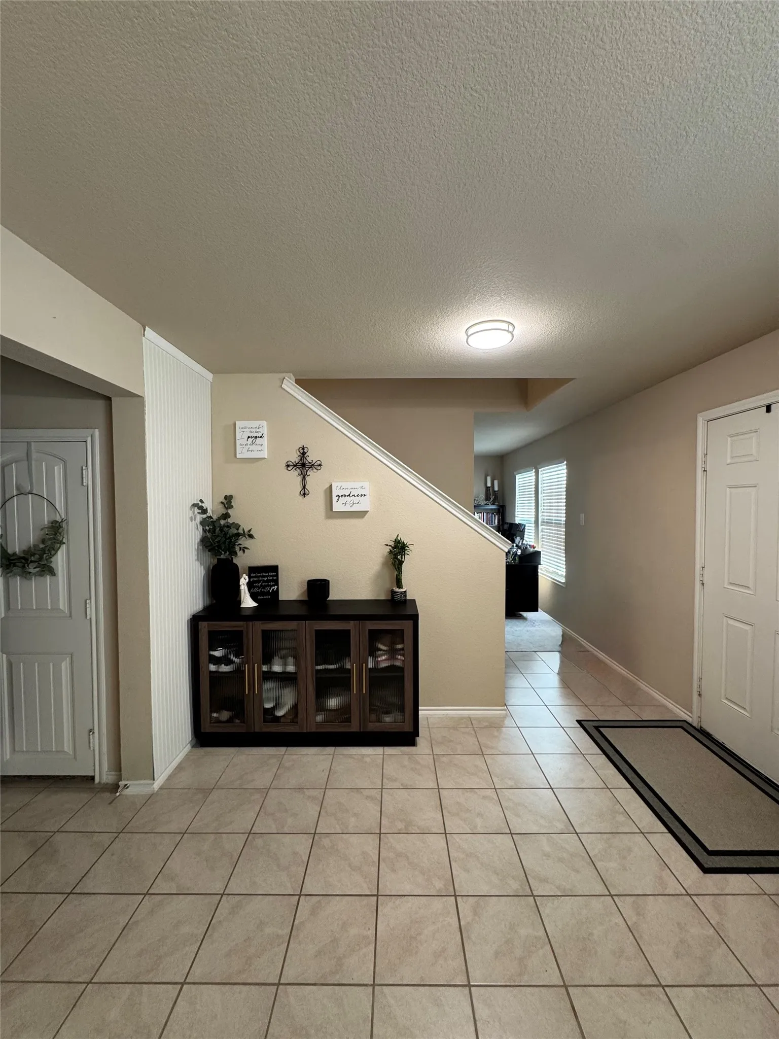 Entryway featuring tile flooring, neutral wall tones, white trim, and a staircase with a white railing