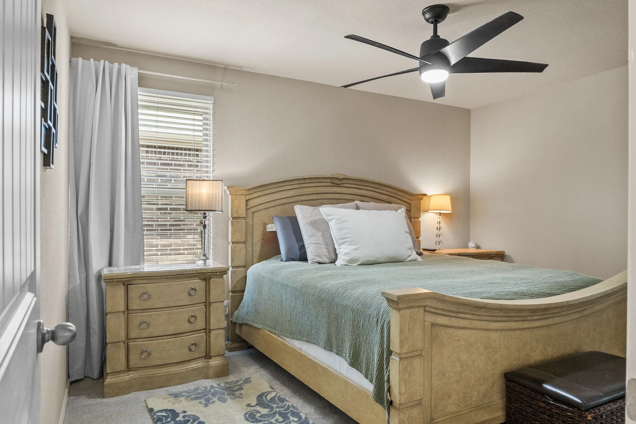 Bedroom featuring carpeted flooring, a window with blinds and drapes, and a ceiling fan with integrated lighting