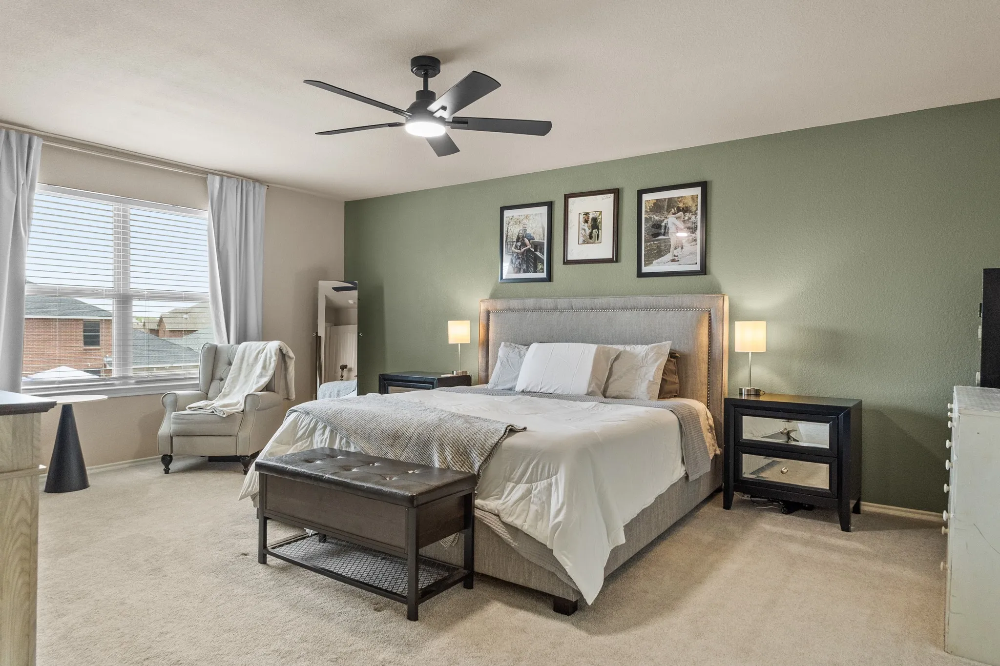 Carpeted room featuring a ceiling fan with integrated lighting, a window with blinds and drapes, and a wall painted in a sage green tone