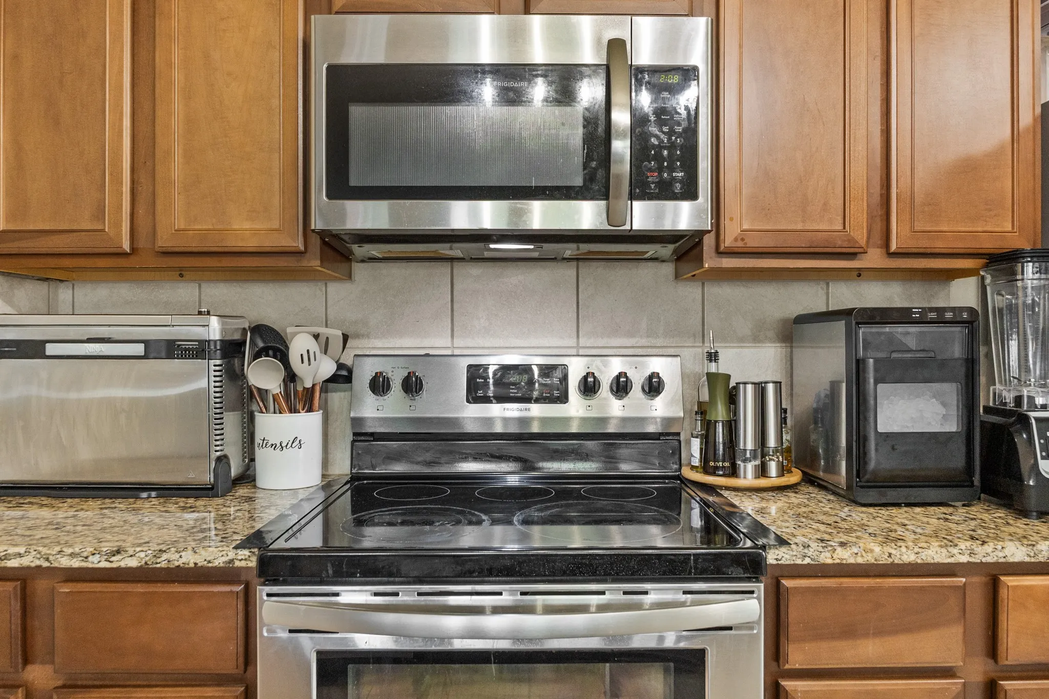 Stainless steel electric range with a black ceramic cooktop, complemented by a coordinating stainless steel microwave oven with integrated exhaust