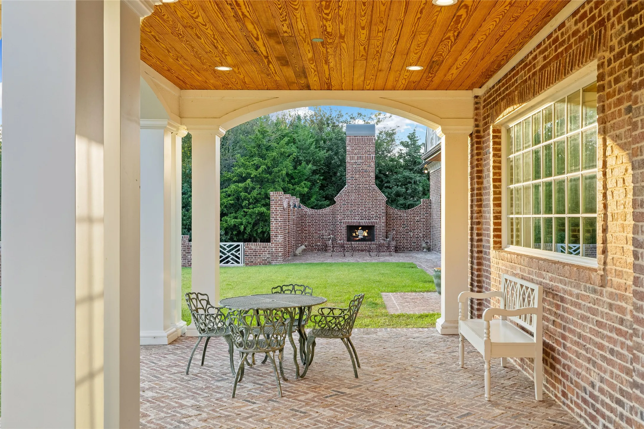 View from covered patio to open outdoor living with fireplace