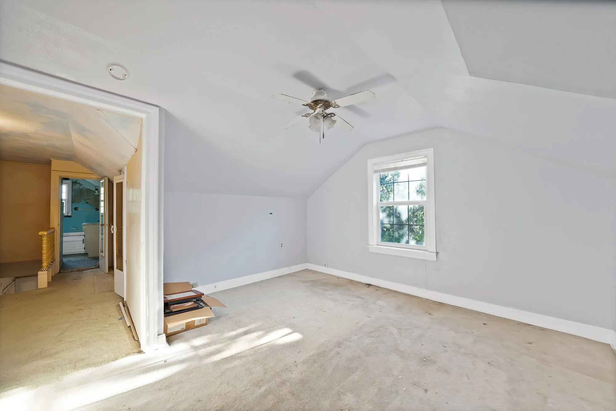 Sloped ceiling architecture with a window, ceiling fan, and carpeted flooring