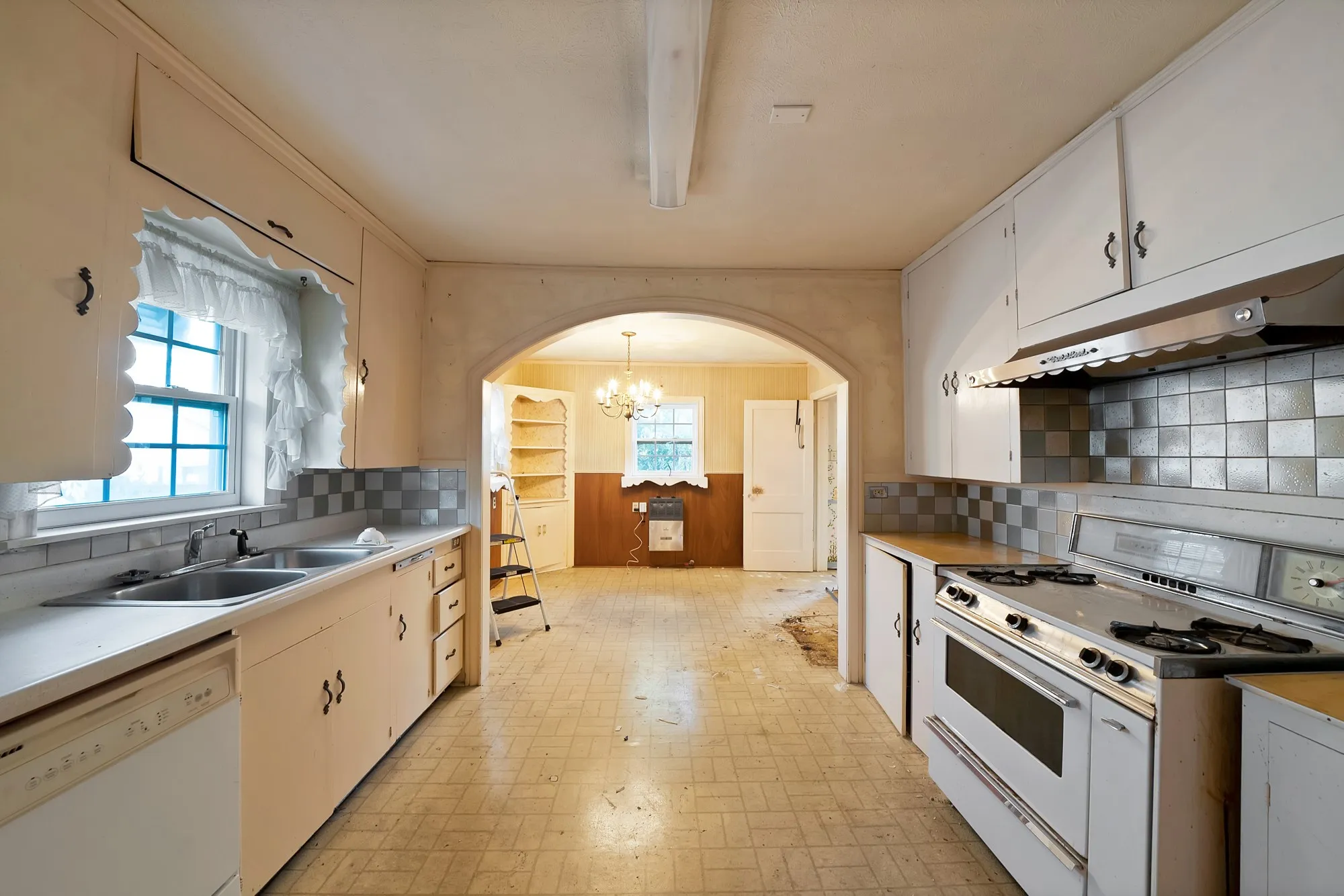 Kitchen featuring extensive cabinetry, dual basin sink, integrated dishwasher, and a built-in range with overhead ventilation