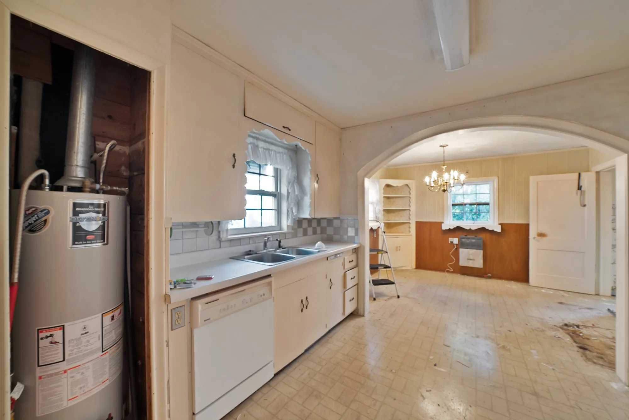 Kitchen space featuring white cabinetry, a double basin sink, and an integrated dishwasher