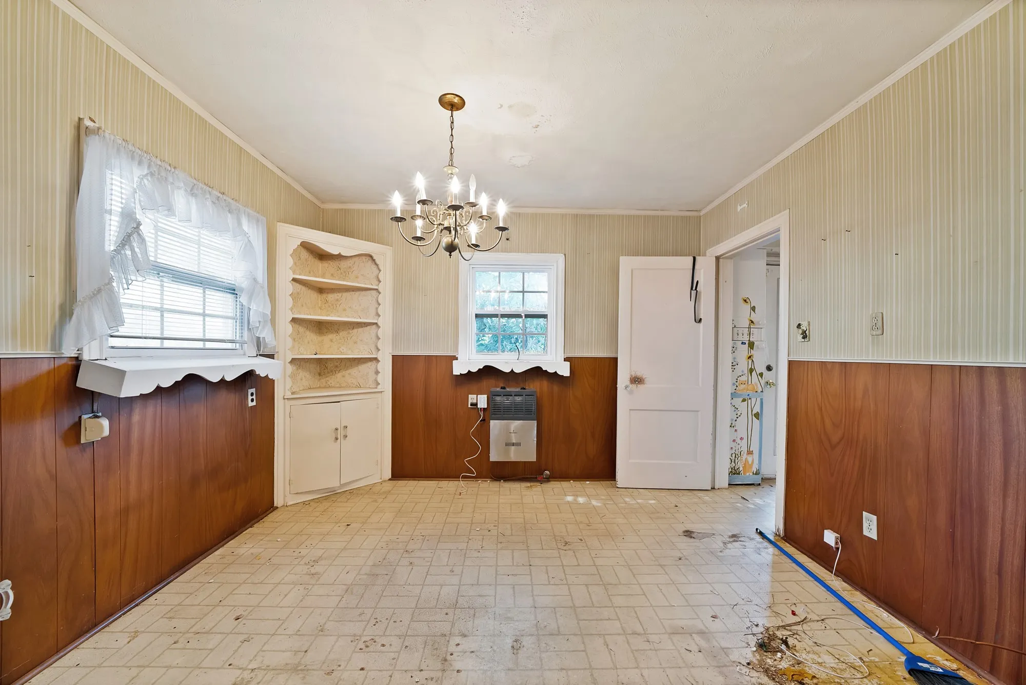 Built-in shelving unit, overhead chandelier, wood-finish wainscoting, and tile flooring