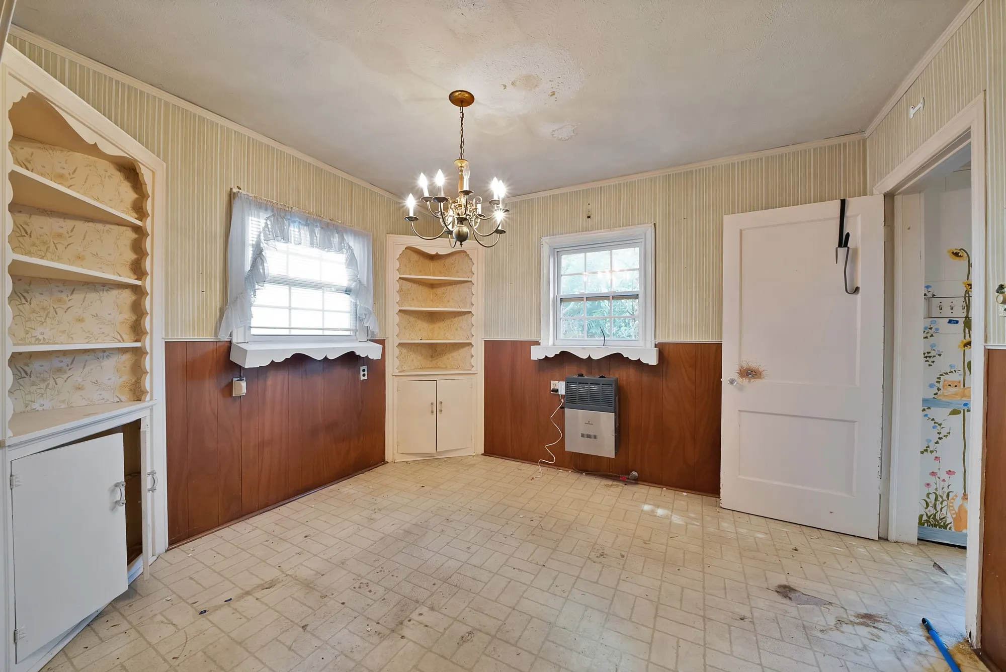 Built-in corner shelving, integrated wall paneling, hard surface flooring, chandelier-style lighting fixture, and a window with natural light